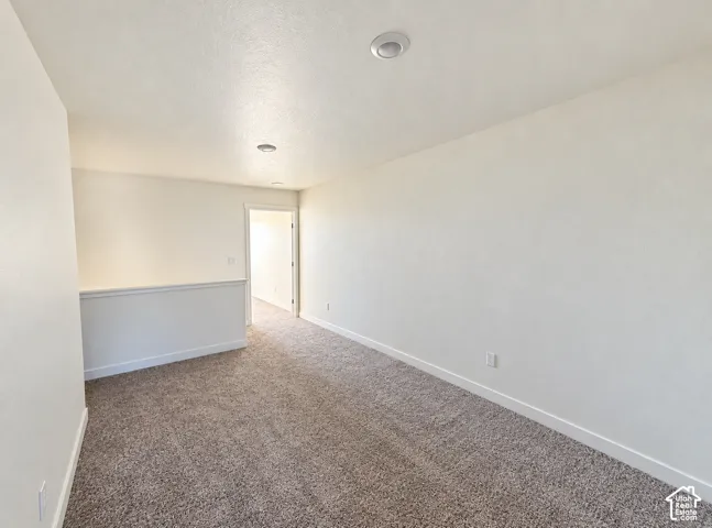 Spacious room with plush carpeting, recessed lighting, and a neutral color palette