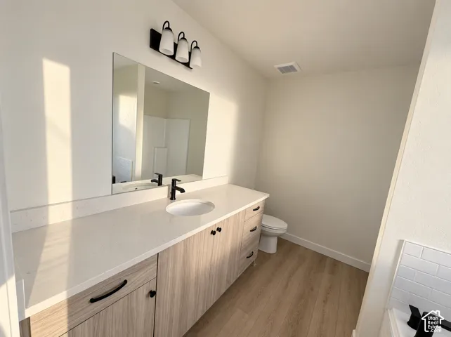 Contemporary vanity with wood-finish cabinetry, white countertop, and integrated sink