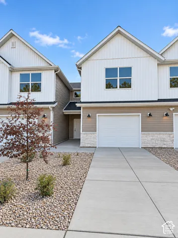 Contemporary townhome featuring a two-tone facade, attached garage, stone accents, and a concrete driveway