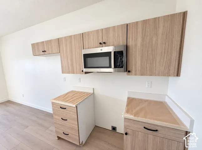 Integrated stainless steel microwave, light wood-finish cabinetry, and light wood-finish flooring