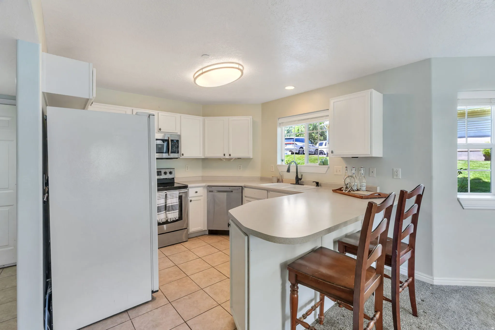 Kitchen featuring white cabinetry, stainless steel appliances, a breakfast bar, stone-finish countertops, and tile flooring