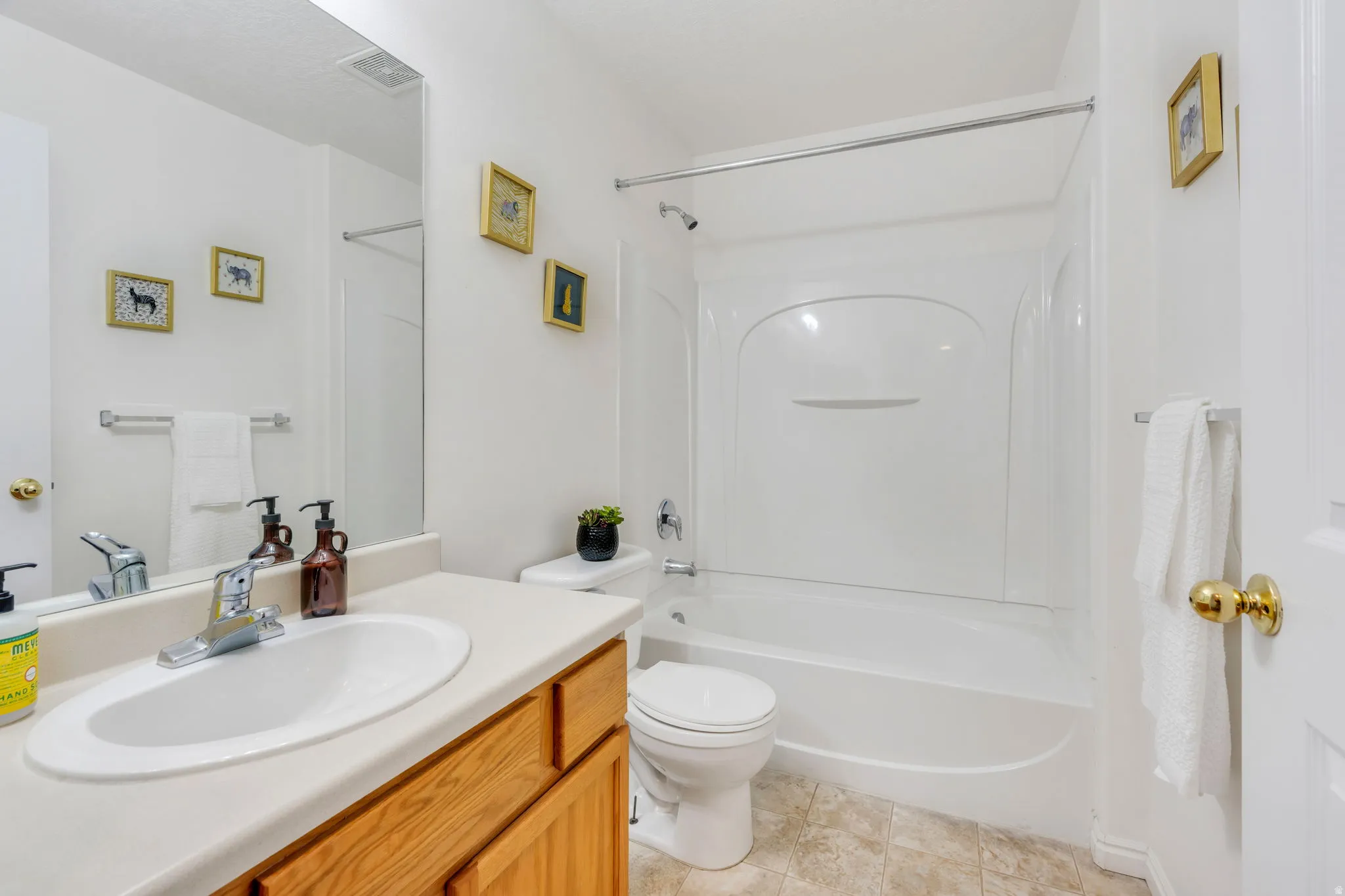 Bathroom featuring a light-toned countertop with an integrated sink, a wood-finish vanity, a full-width mirror, and a white tub/shower combination