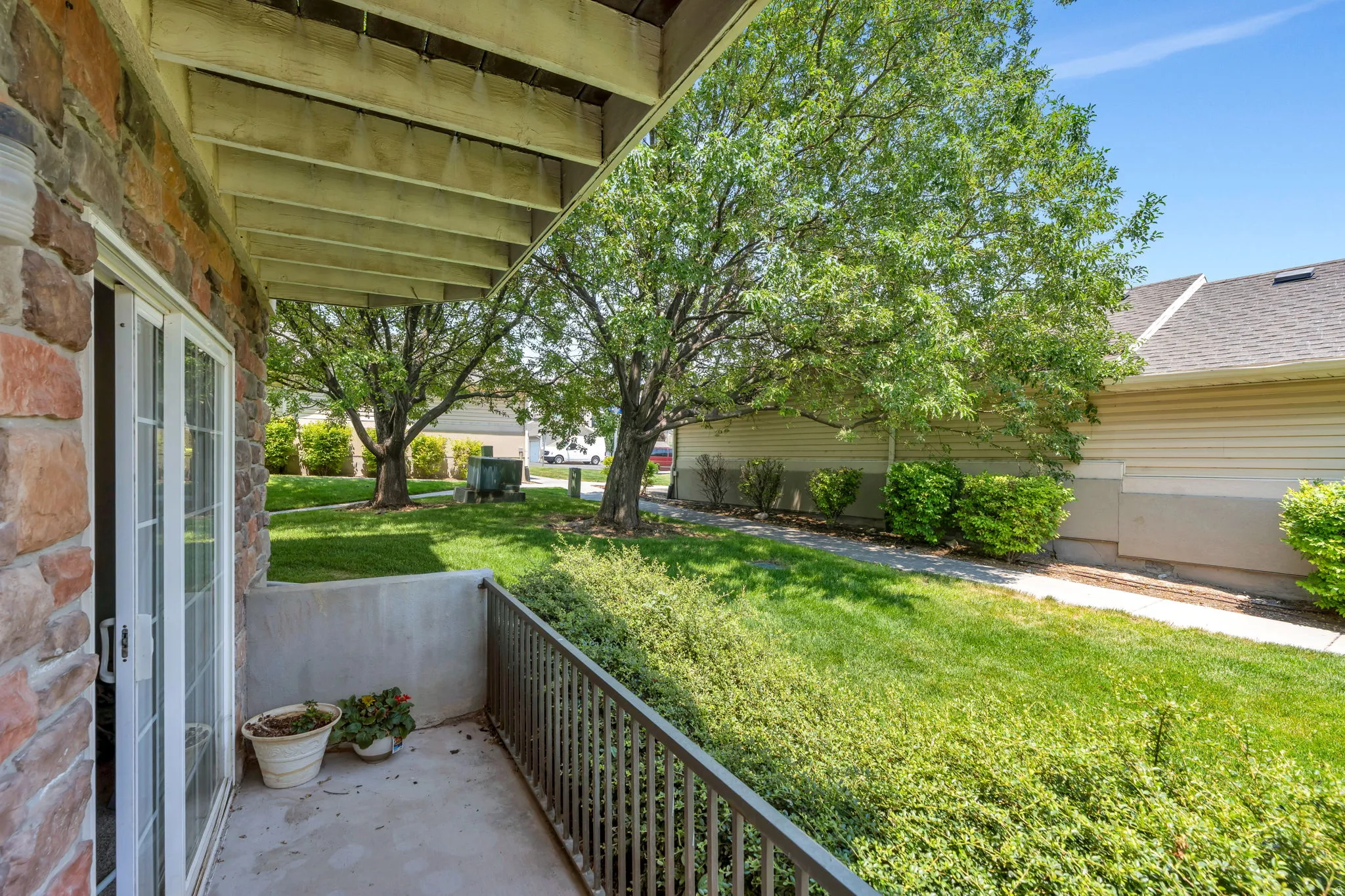 Private patio featuring a stone-clad wall and a metal railing