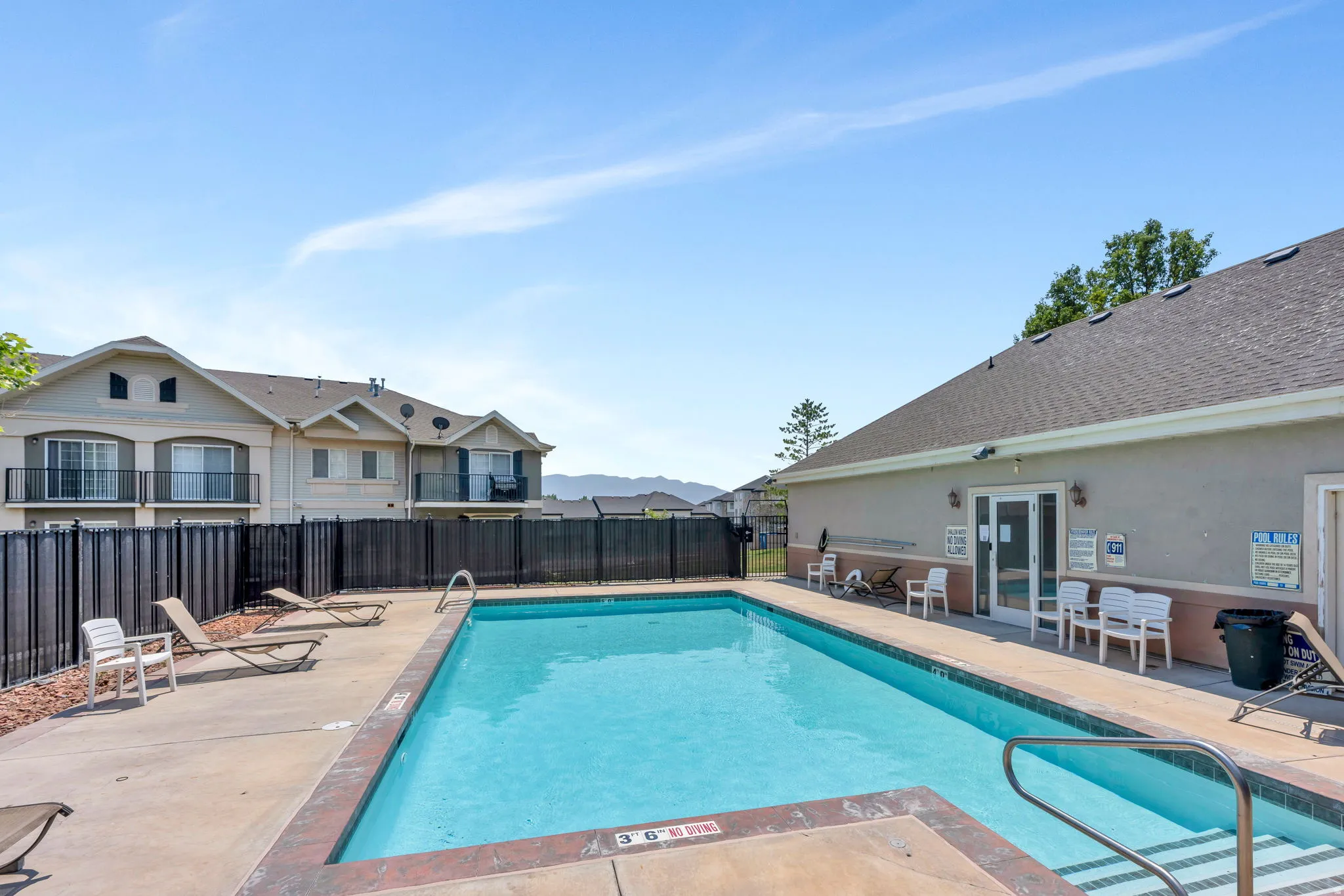 Outdoor swimming pool with integrated steps, surrounded by a concrete patio with a contrasting border