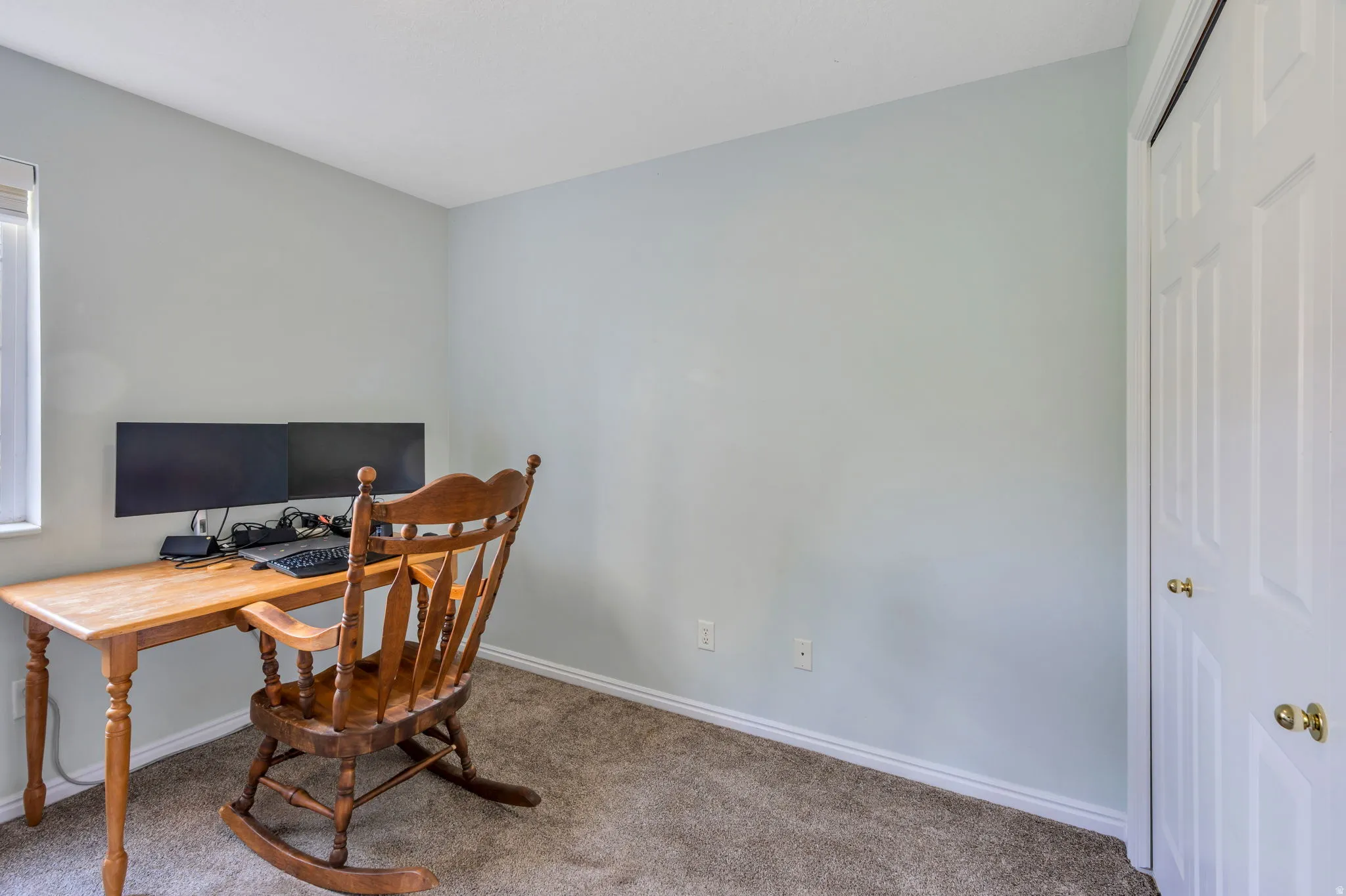 Carpeted room with light blue wall paint, a window featuring a white blind, and a white bi-fold closet door with brass hardware