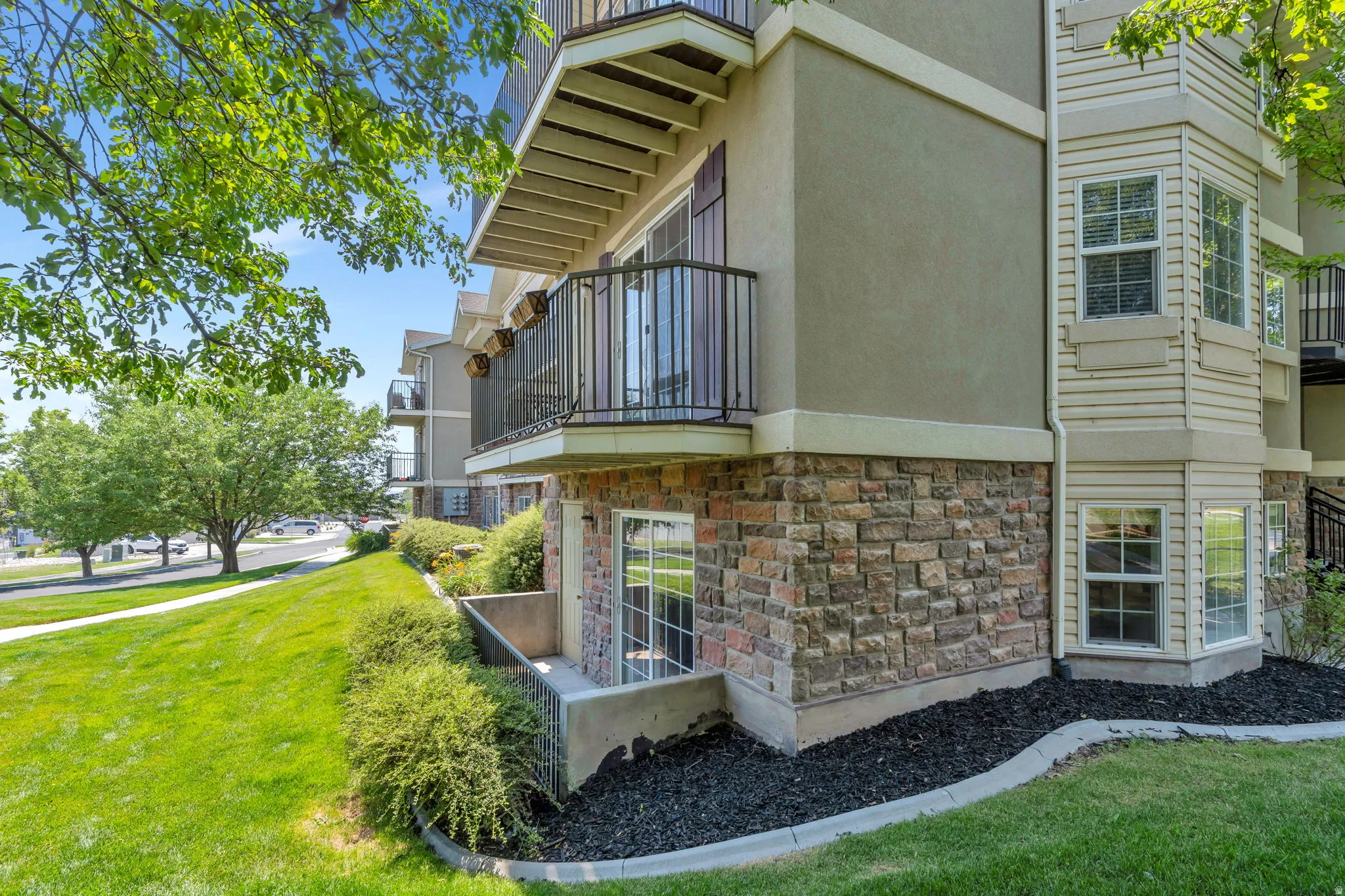 Exterior architecture featuring a stone veneer foundation, stucco siding, and bay windows