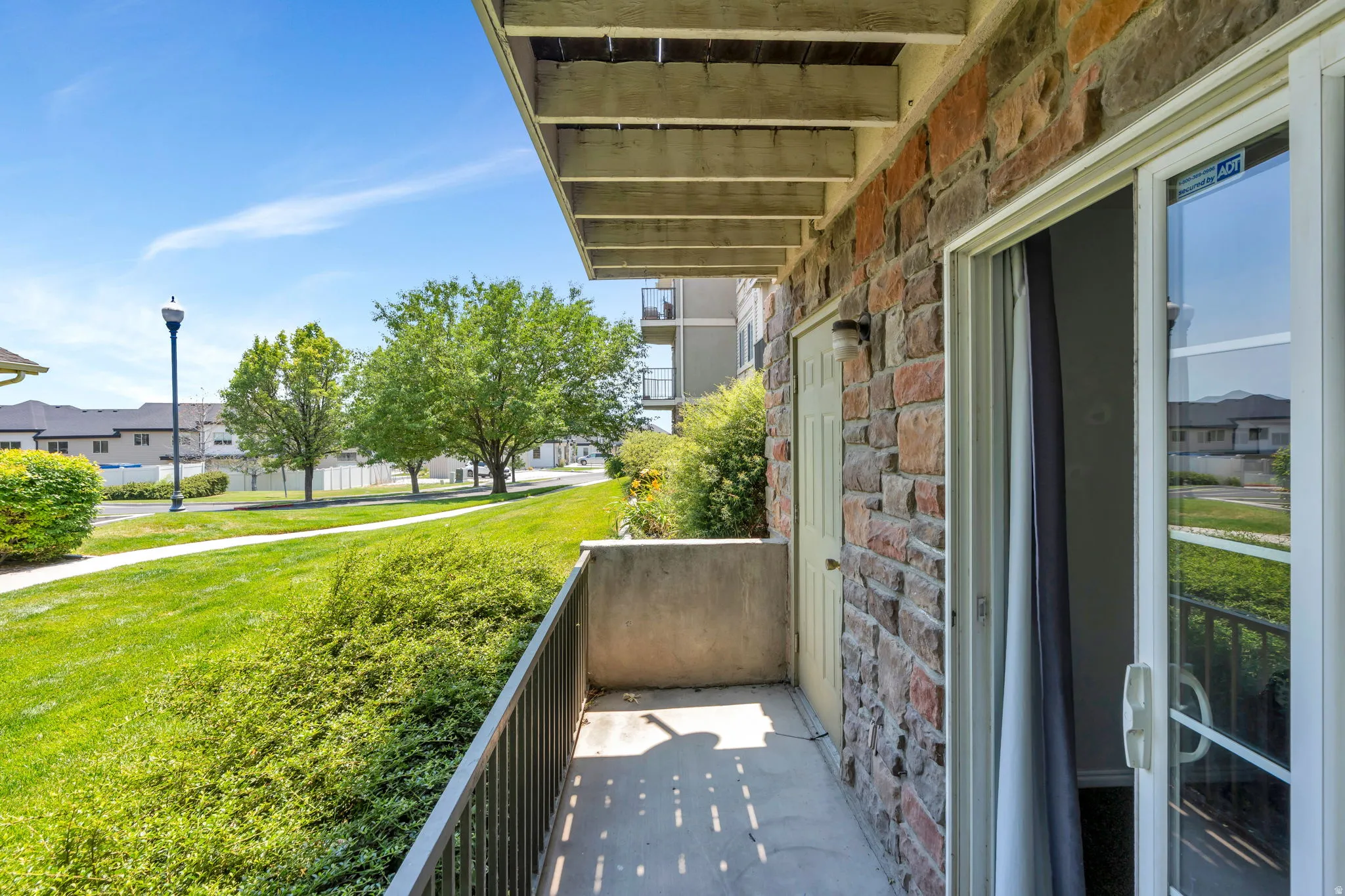 Private balcony featuring a stone veneer exterior, sliding glass door, exterior storage access, and metal railing