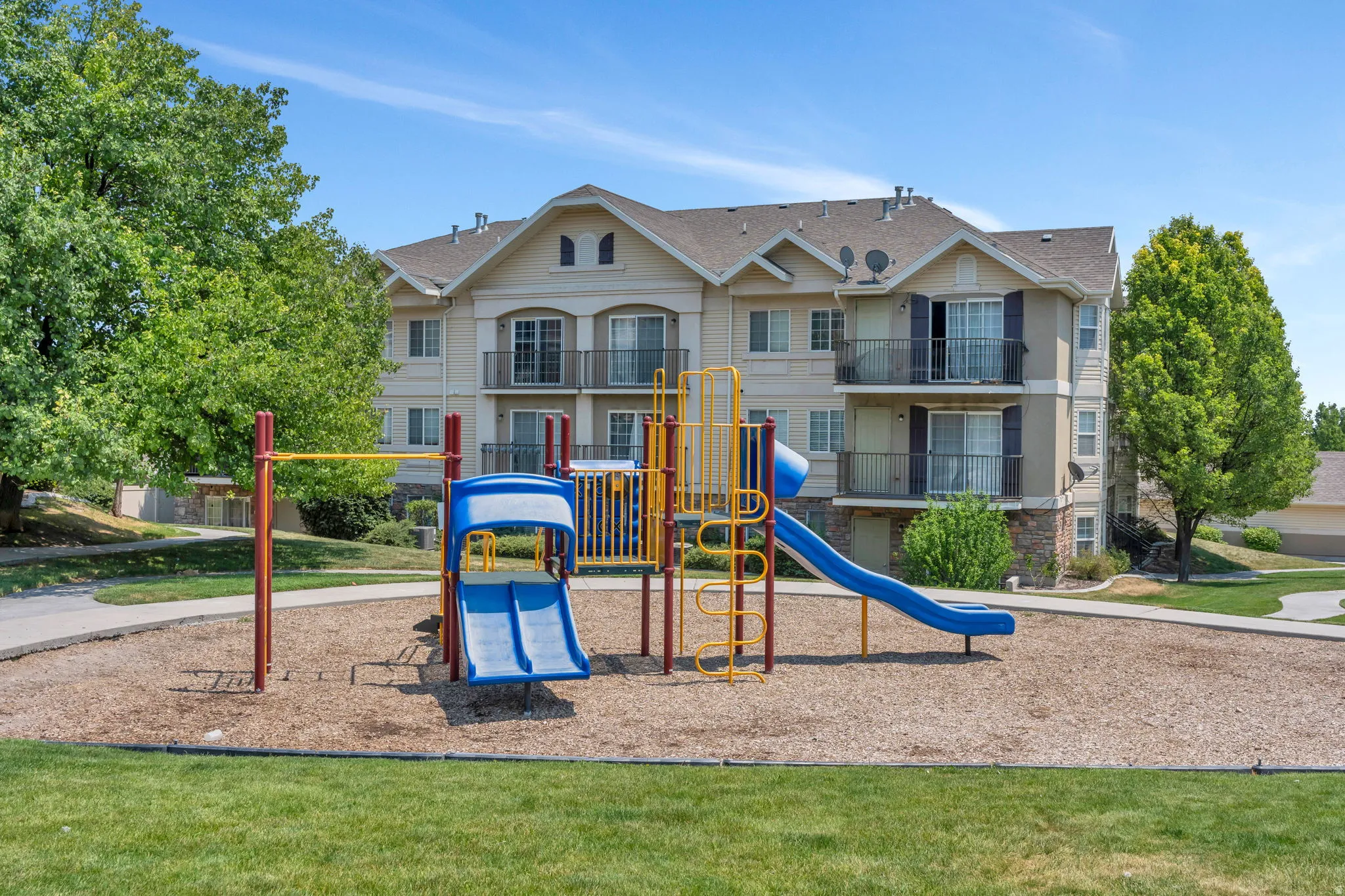 Community playground featuring a blue and yellow play structure over wood chips