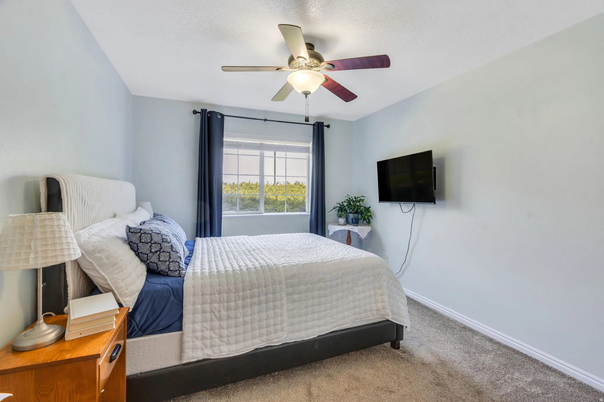 Room featuring a ceiling fan, wall-mounted television, and a window with blinds