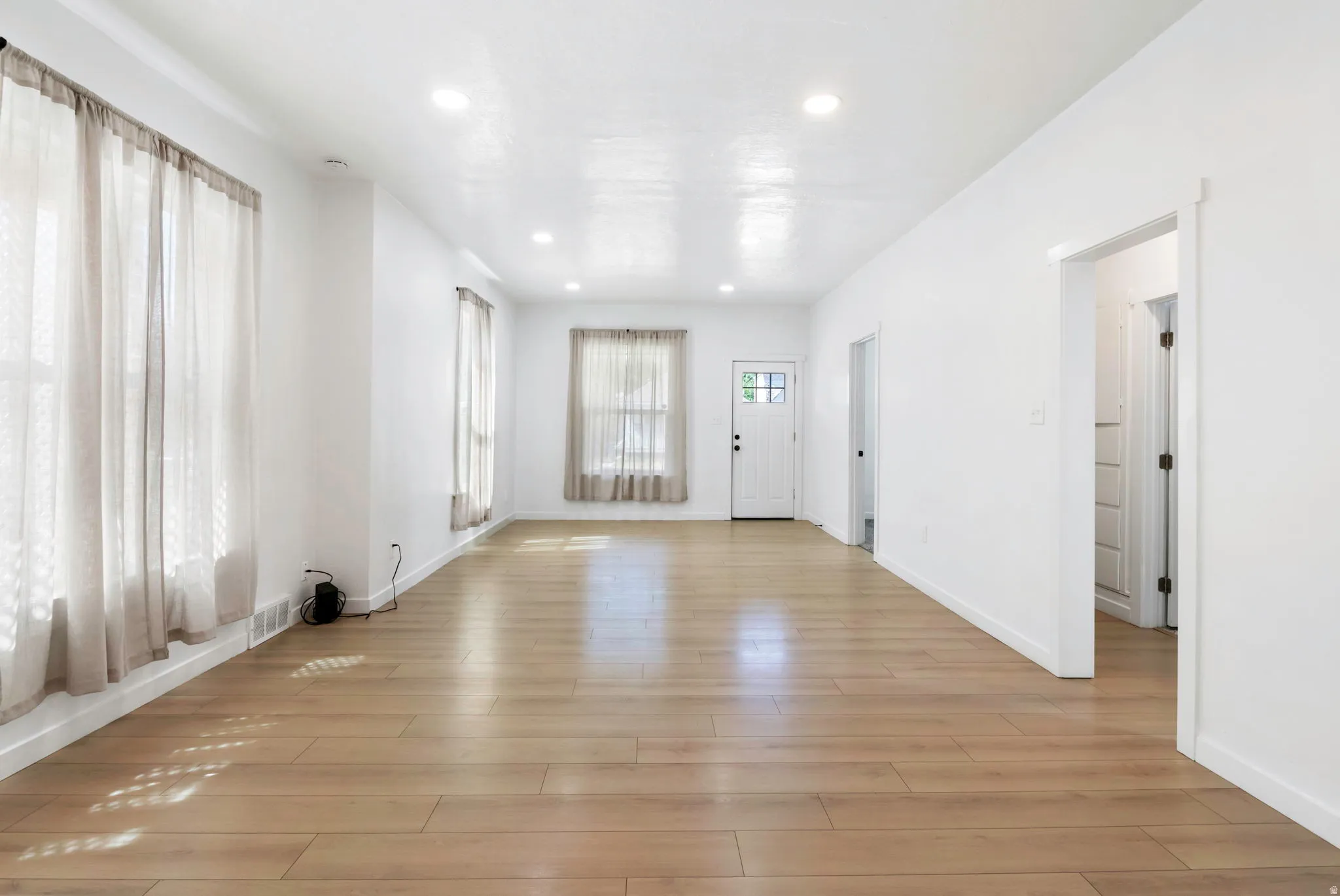 Spacious living area featuring light wood-finish flooring and recessed lighting