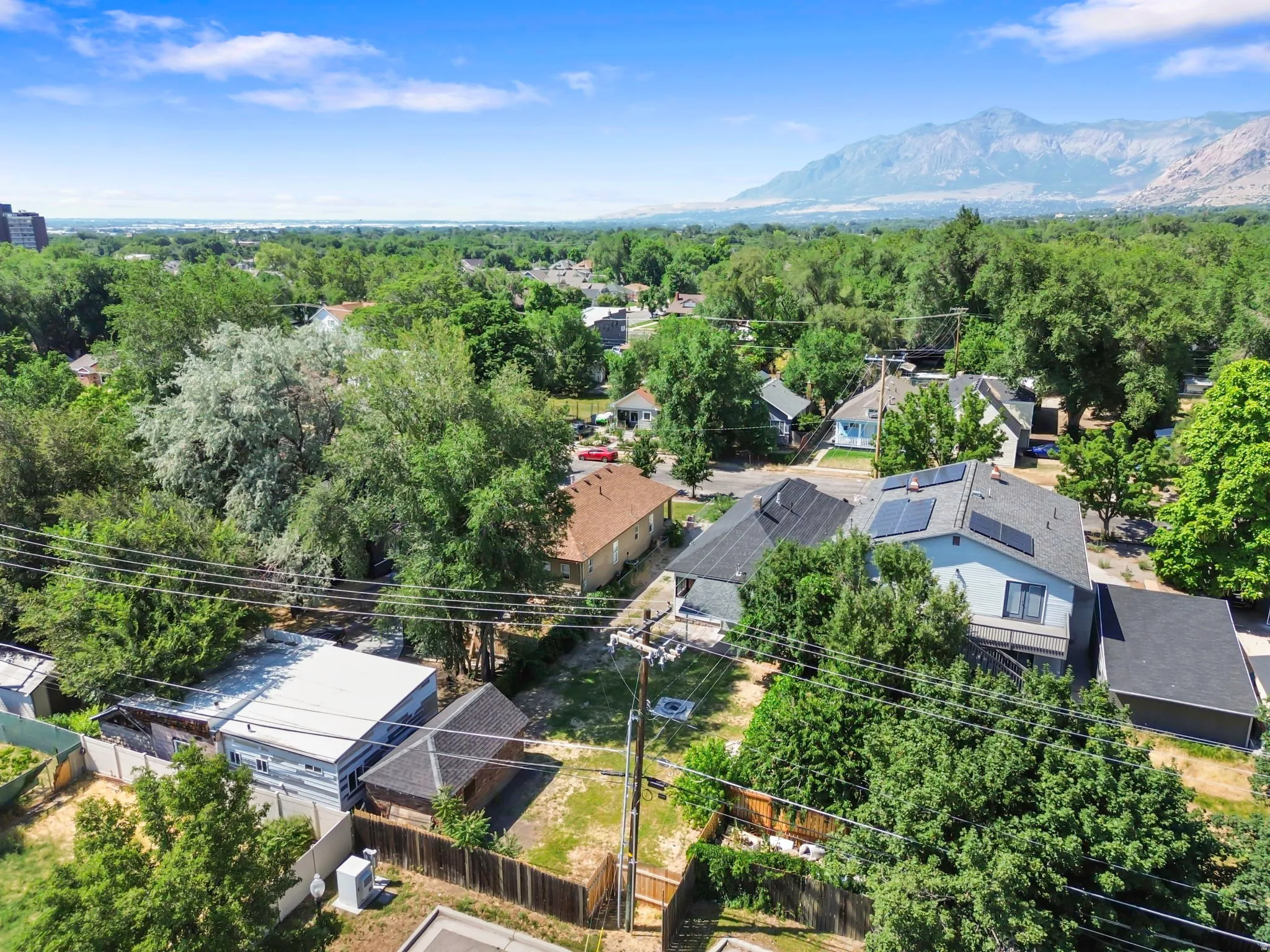 Aerial perspective showcasing a residential neighborhood with mature trees and mountain range backdrop