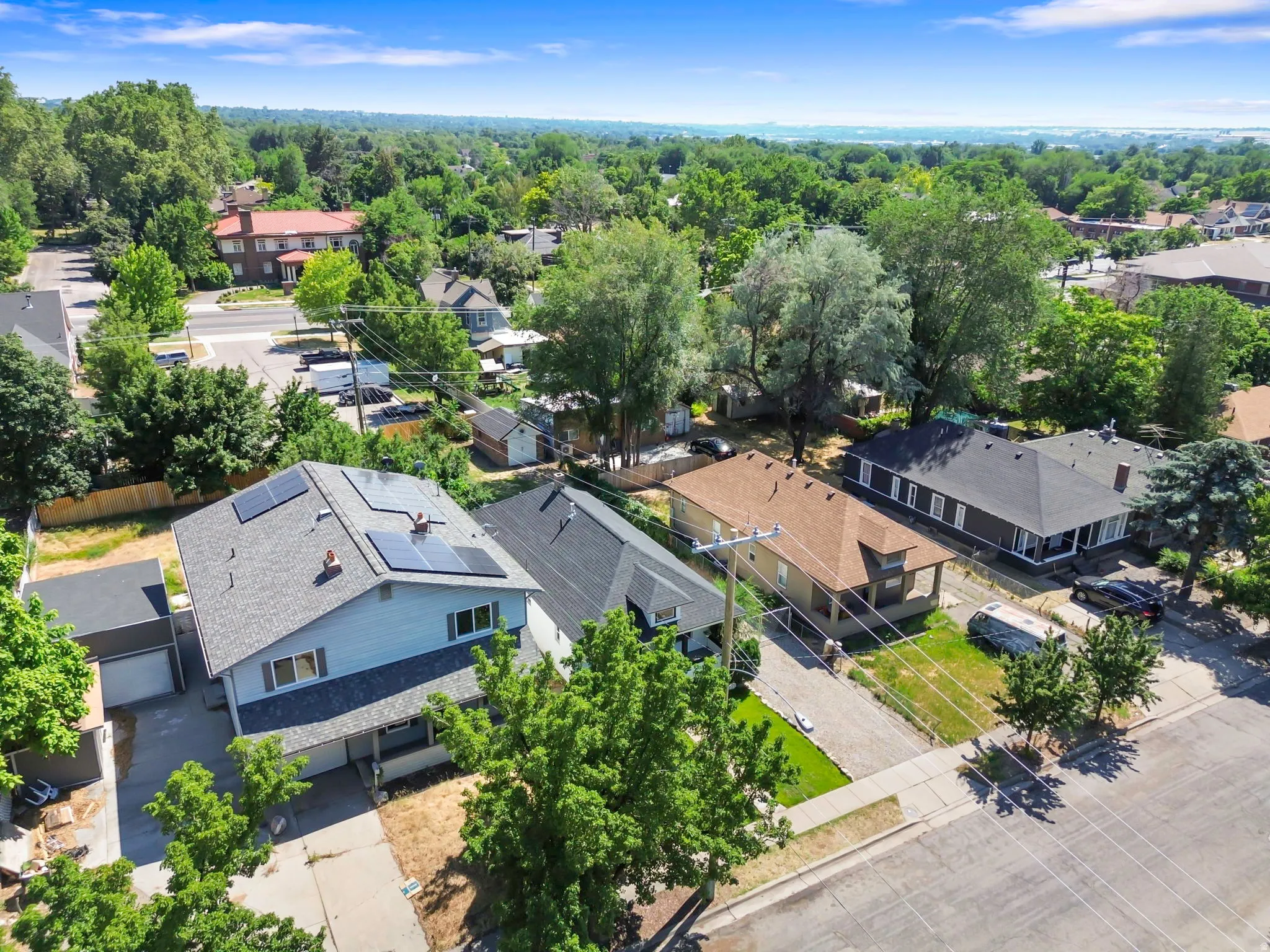 Two-story residence featuring a light blue exterior, dark gray shingle roof, and solar panels