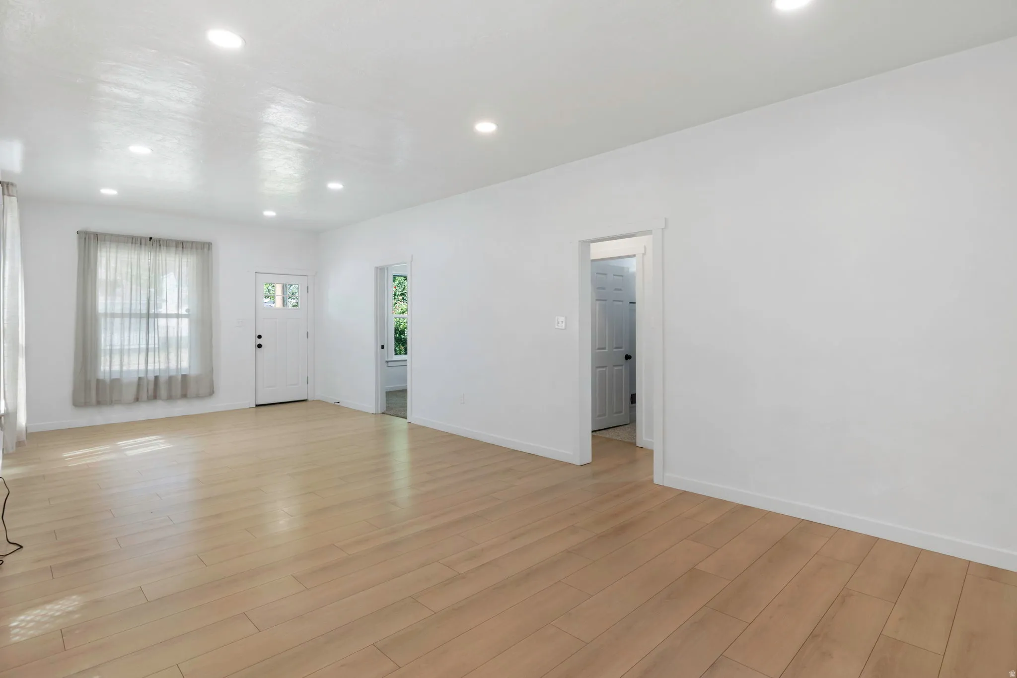 Spacious room featuring wood-finish flooring, recessed lighting, and white baseboards