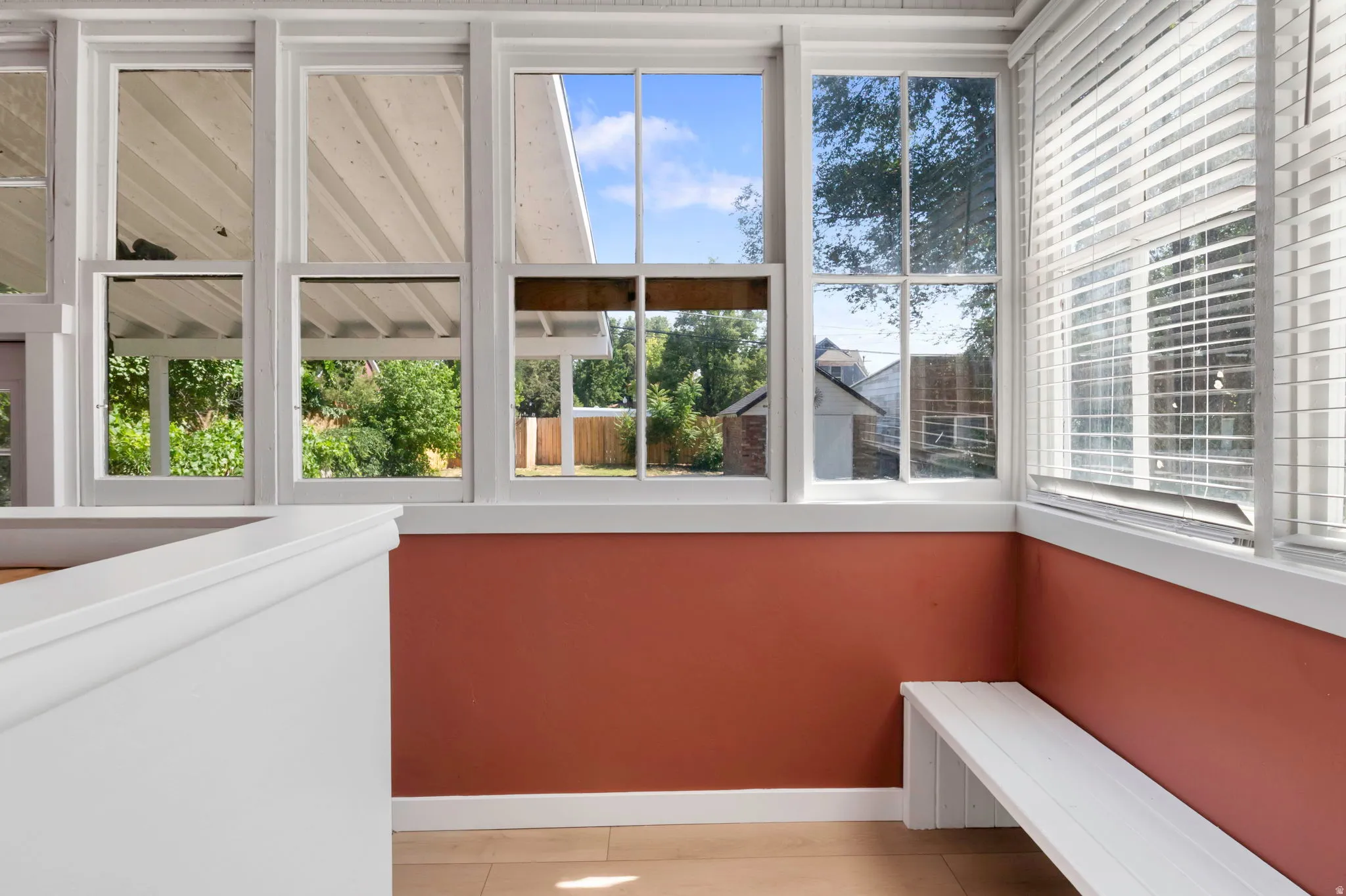 Sunroom featuring multiple vertical windows, a built-in white bench, white trim work, and wood-finish flooring