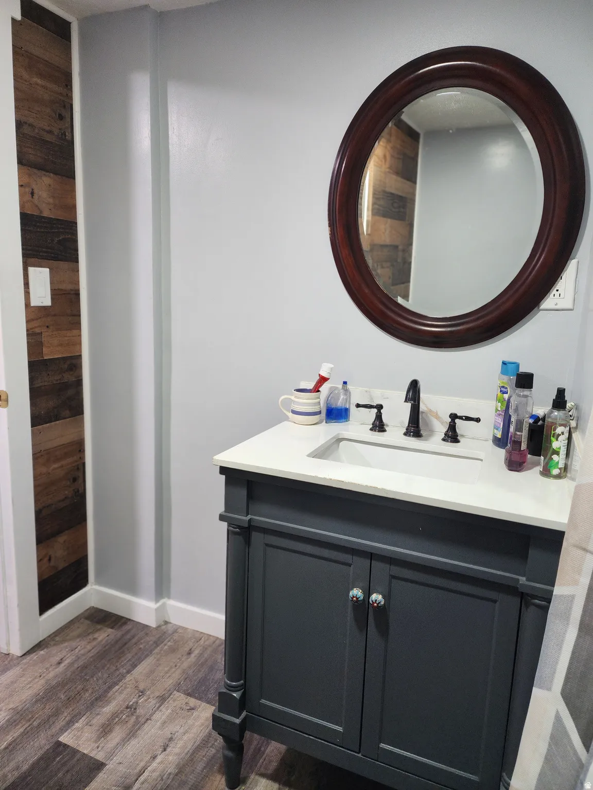 Vanity with an integrated sink and white countertop, framed by a dark wood-finish mirror