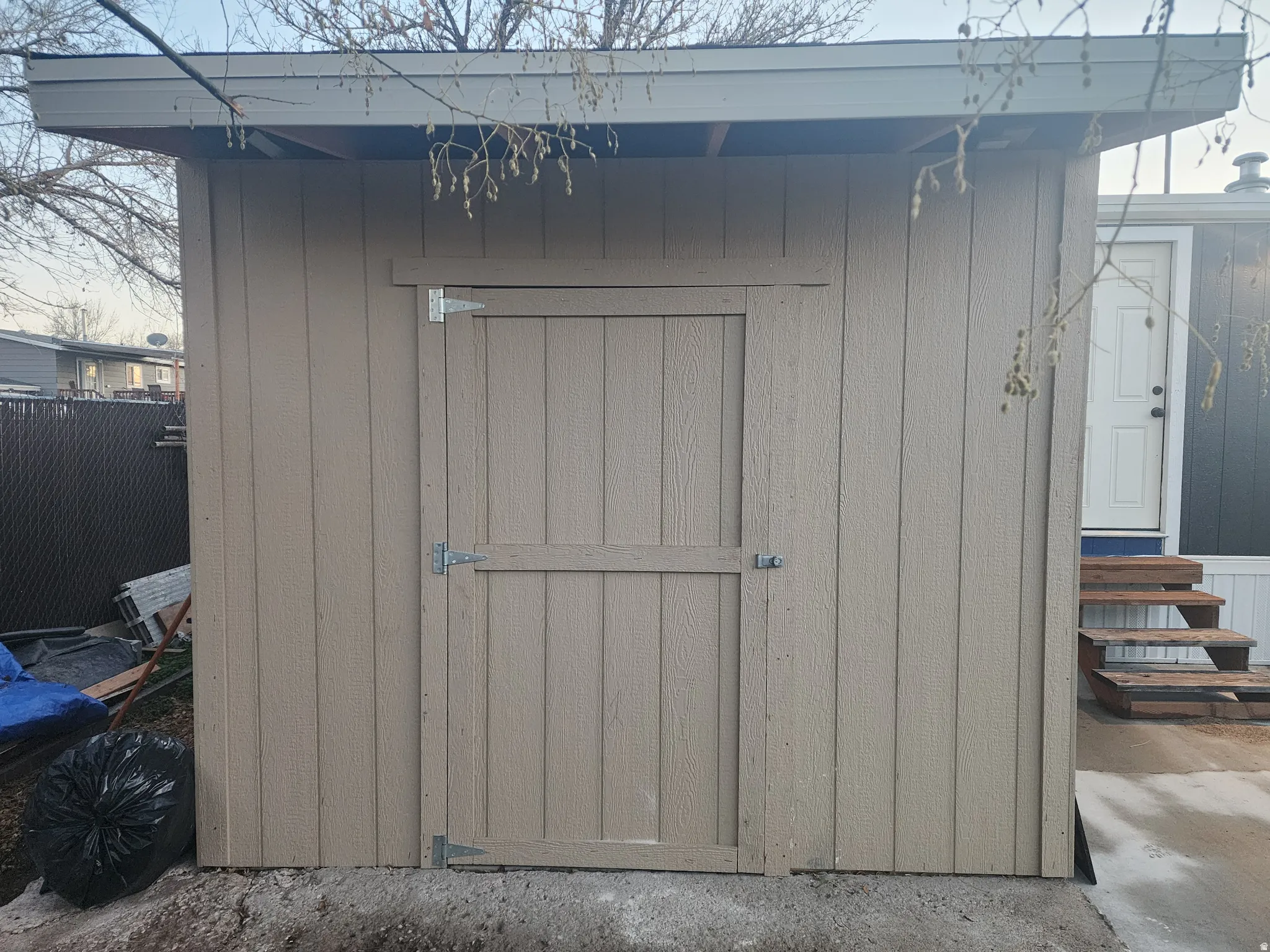 Shed with vertical panel siding, a sloped roof, and a single hinged door