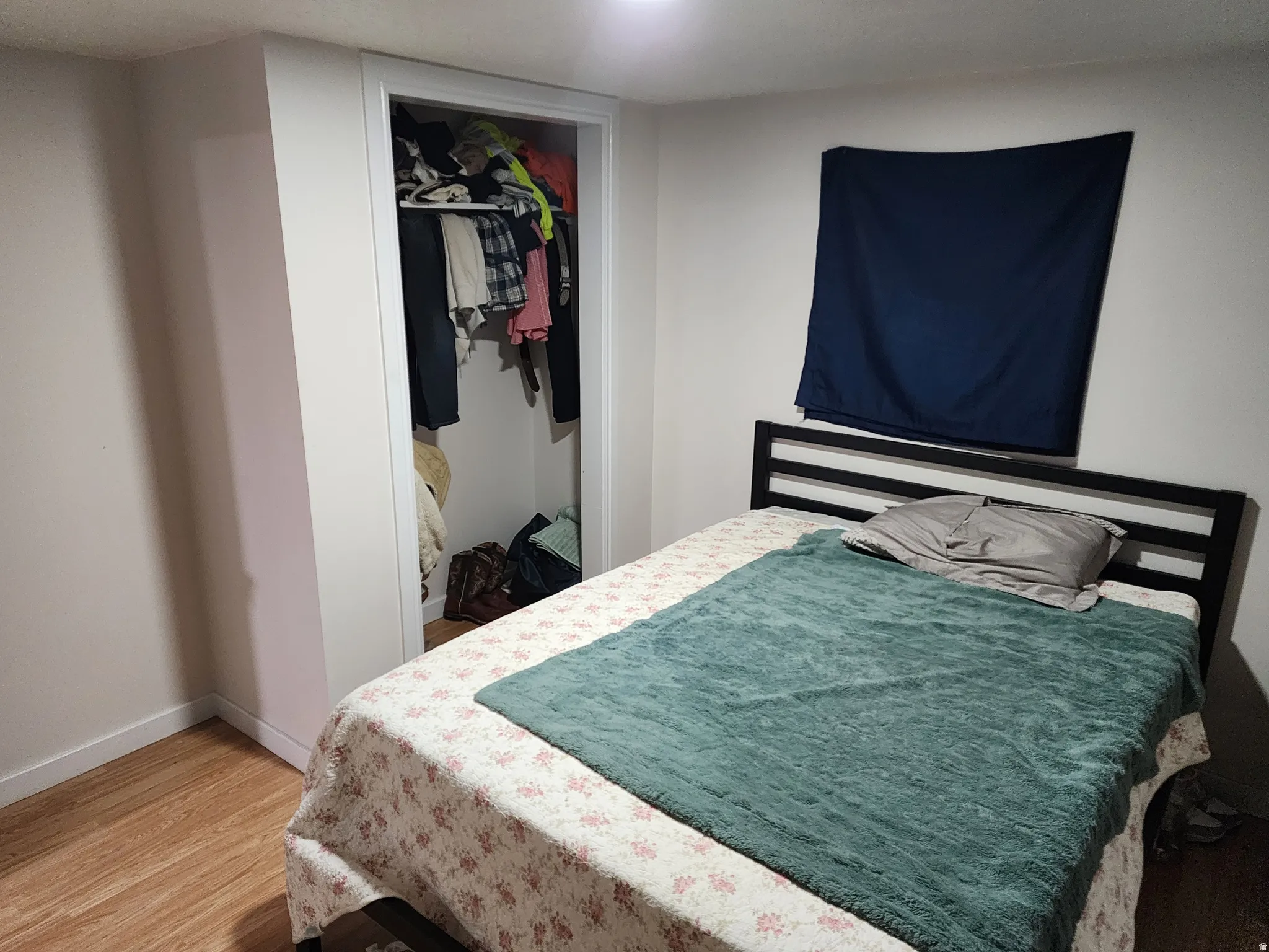 Room featuring wood-finish flooring, white baseboards, and a built-in closet with shelving
