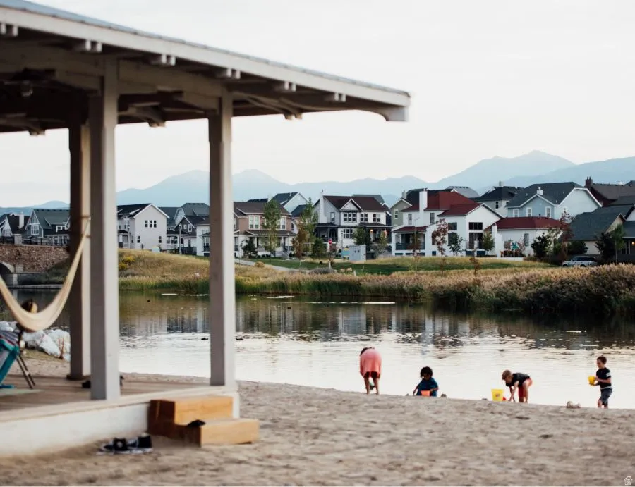 Lakeside community featuring a sandy beach area and a covered pavilion with a hammock