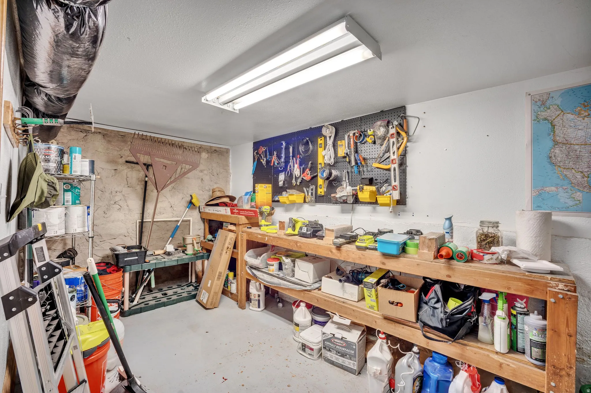 2-bedroom floorplan (614) utility room featuring a built-in workbench, pegboard organization system, overhead fluorescent lighting, and concrete flooring