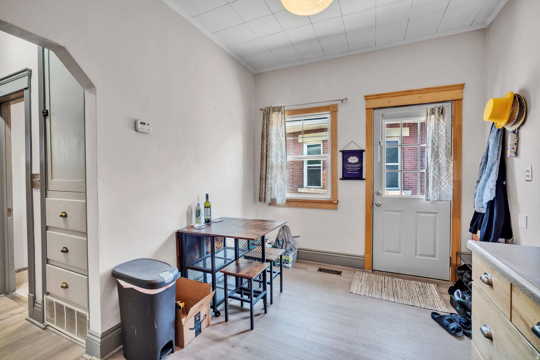 2-bedroom floorplan (614) kitchen area featuring wood-finish flooring, a built-in storage cabinet with drawer pulls, a window with natural wood trim, and a white exterior door with glass panels