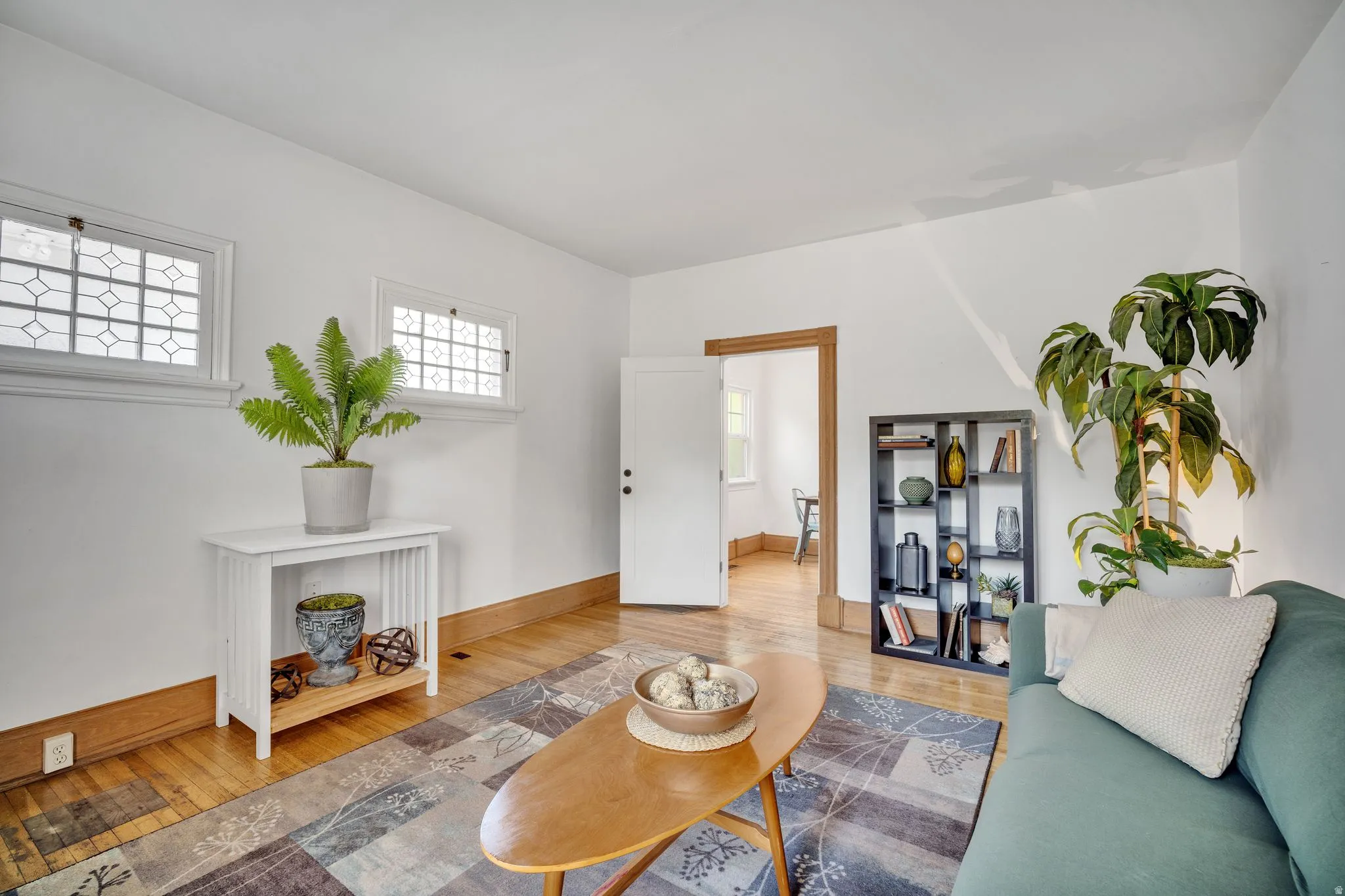 2-bedroom floorplan (614) living room featuring two transom windows with decorative panes, warm wood-finish flooring, and white baseboards