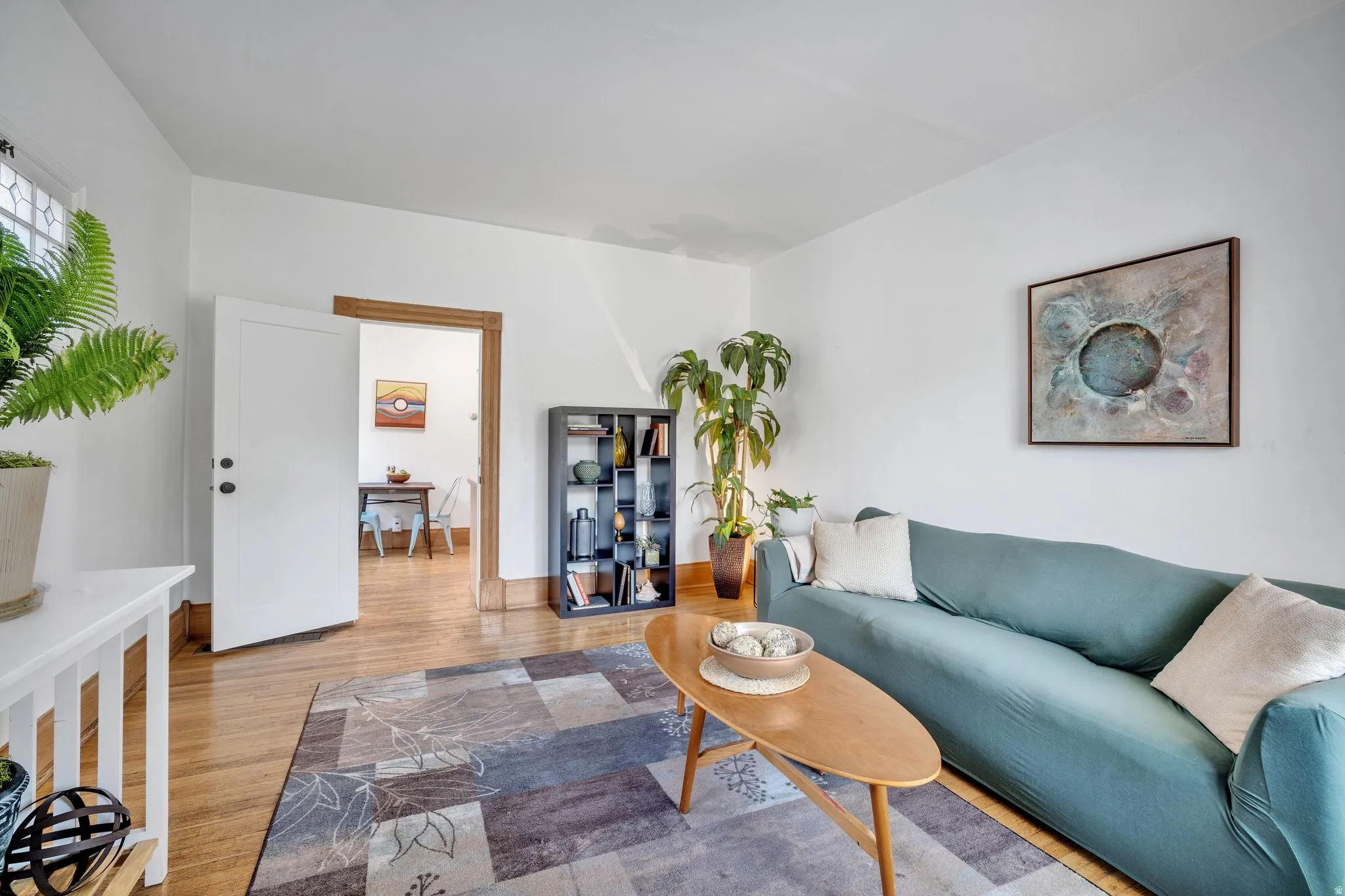 2-bedroom floorplan (614) interior living room space featuring hardwood flooring, white walls, and a decorative stained-glass window