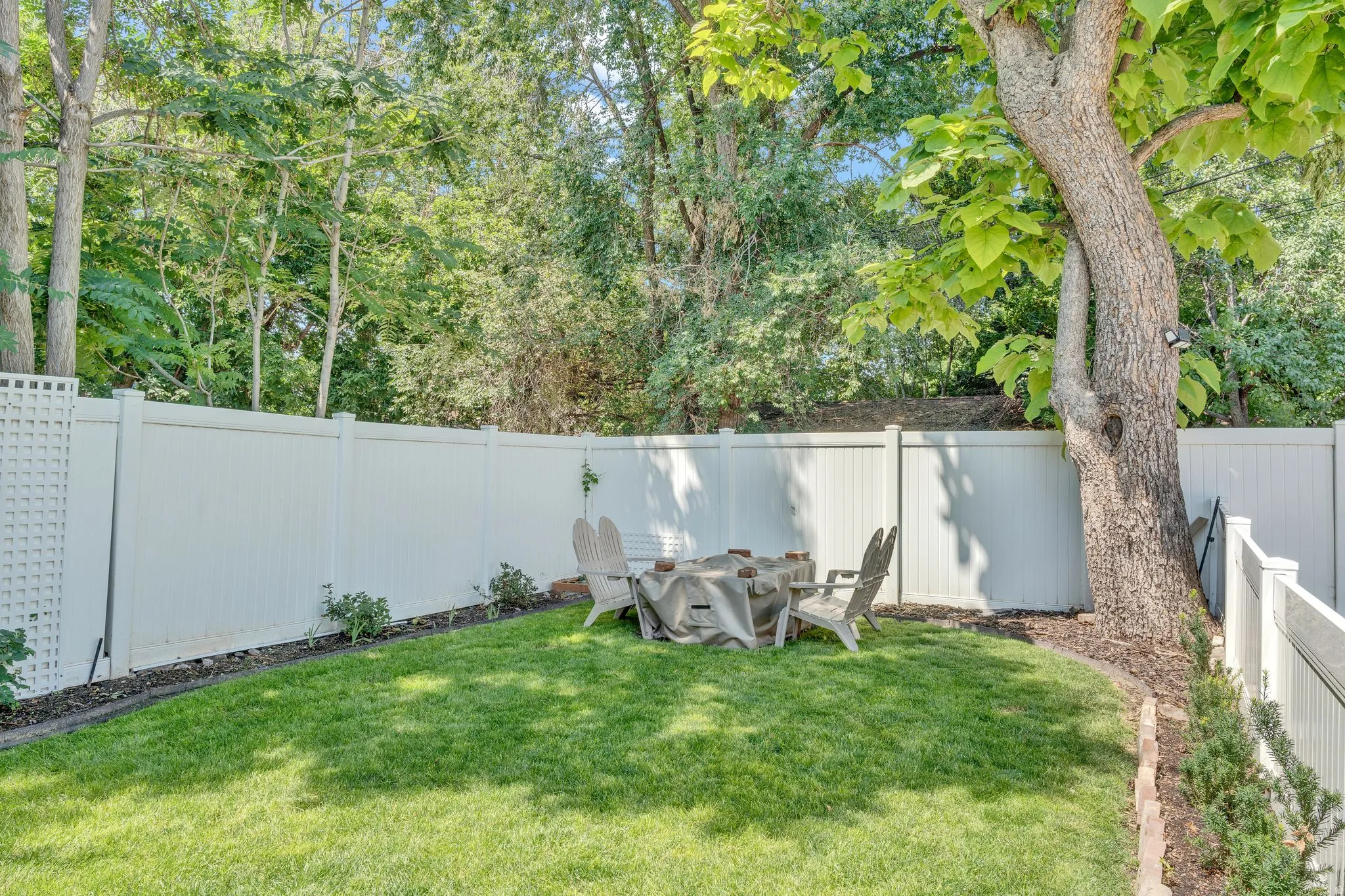 Expansive green lawn with a white privacy fence