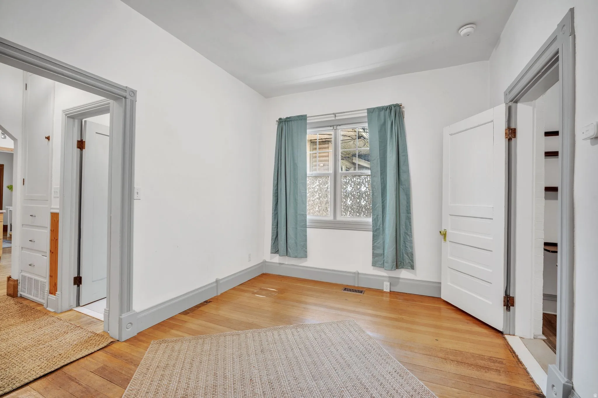 2-bedroom floorplan (614) bedroom #2 with hardwood flooring and crisp white walls featuring a window with patterned glass and a white paneled door