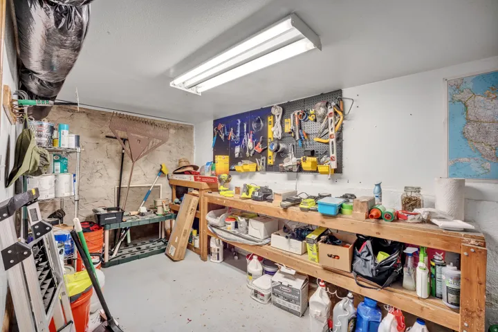 2-bedroom floorplan (614) utility room featuring a built-in workbench, pegboard organization system, overhead fluorescent lighting, and concrete flooring