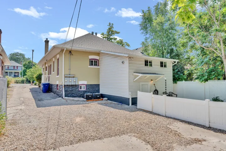 Gravel driveway leading to a private outdoor area featuring a white vinyl fence