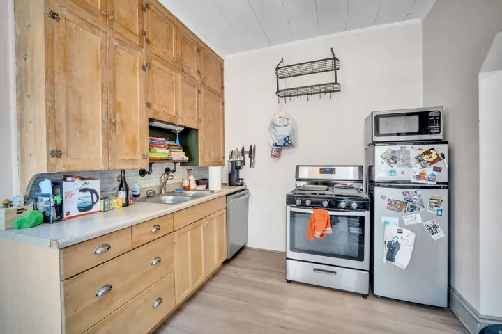 1 bedroom floorplan (618) kitchen featuring extensive wood cabinetry, wood-finish flooring, a stainless-steel gas range, and a stainless-steel refrigerator