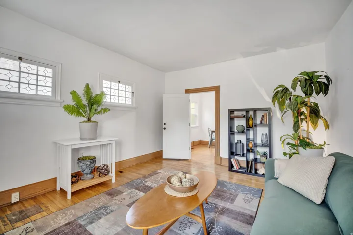 2-bedroom floorplan (614) living room featuring two transom windows with decorative panes, warm wood-finish flooring, and white baseboards