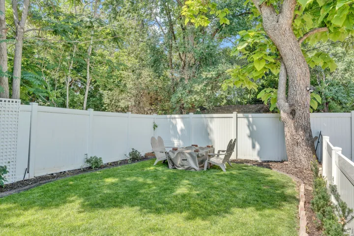 Expansive green lawn with a white privacy fence
