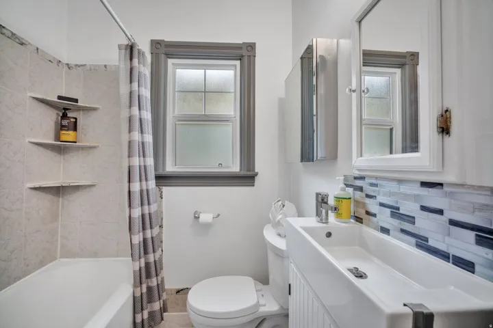2-bedroom floorplan (614) bathroom featuring a white bathtub, tiled shower surround with corner shelves, and a window with decorative trim