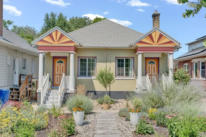 Charming duplex exterior featuring two distinct entryways with decorative sunburst pediments