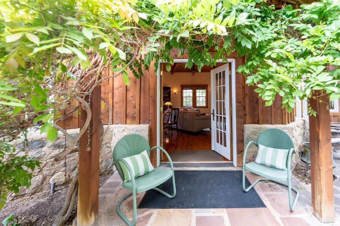 Entryway featuring French doors, wood-paneled siding, a stone foundation, and natural stone tile flooring