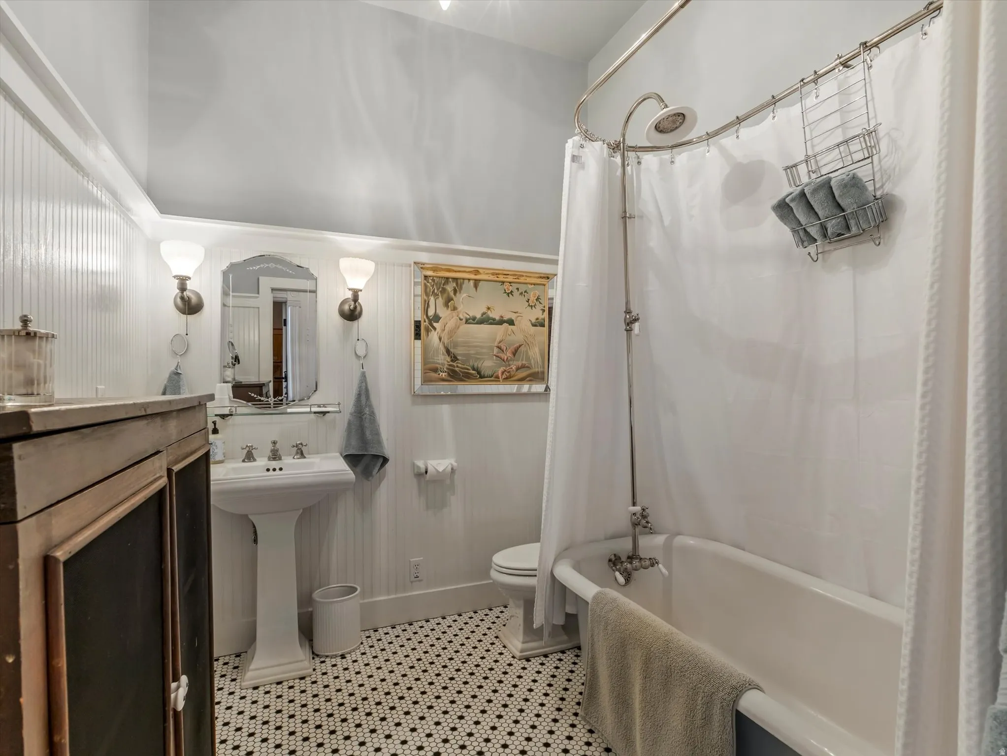 ADU Bathroom featuring a pedestal sink, wall-mounted sconces, and beadboard paneling
