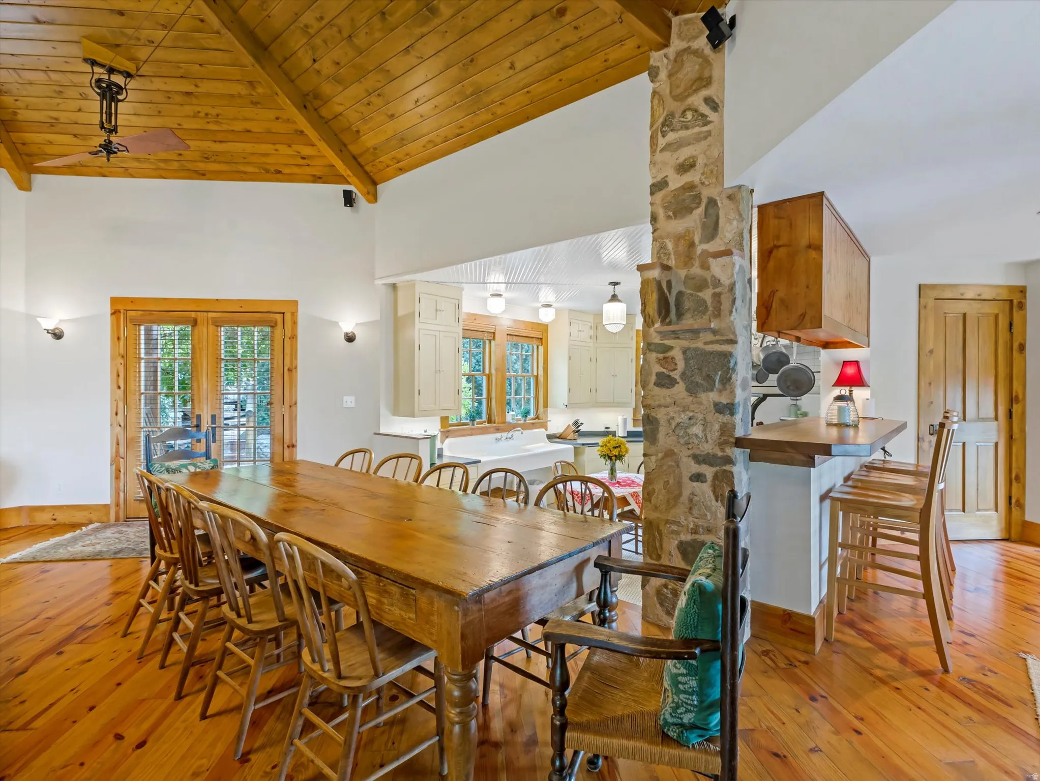 Vaulted wood-paneled ceiling above a spacious dining area featuring wood-finish flooring and French doors