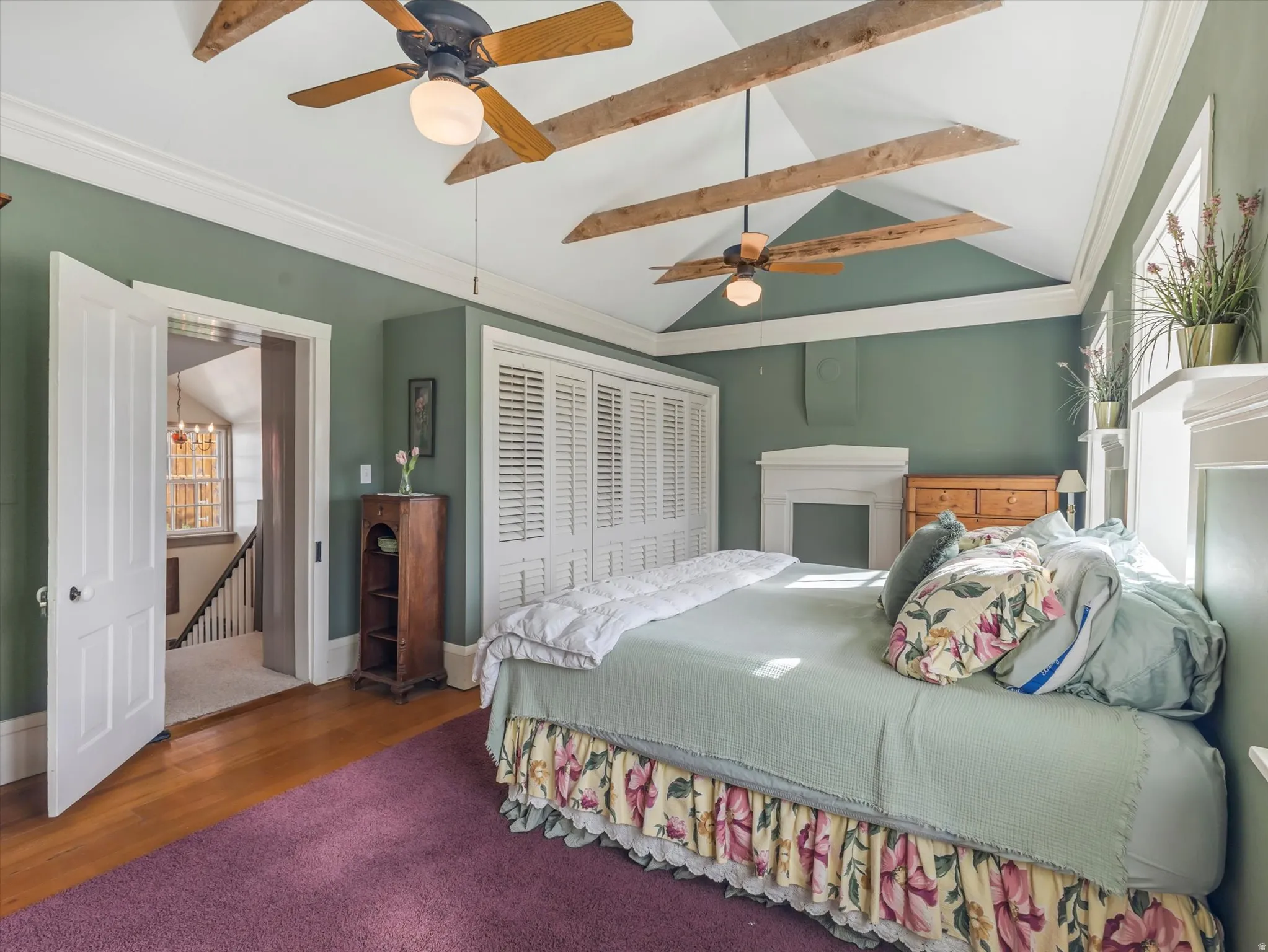 Vaulted ceiling featuring exposed wood beams and twin ceiling fans