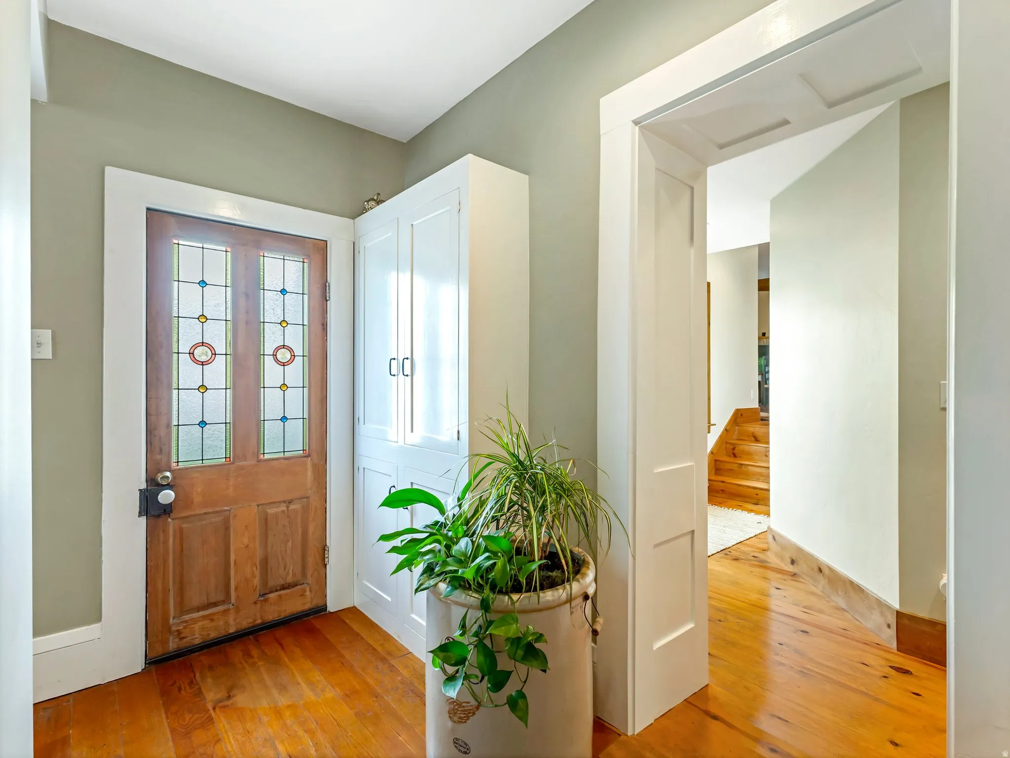 Entryway featuring a wood door with stained-glass panels, rich wood-finish flooring, and white trim