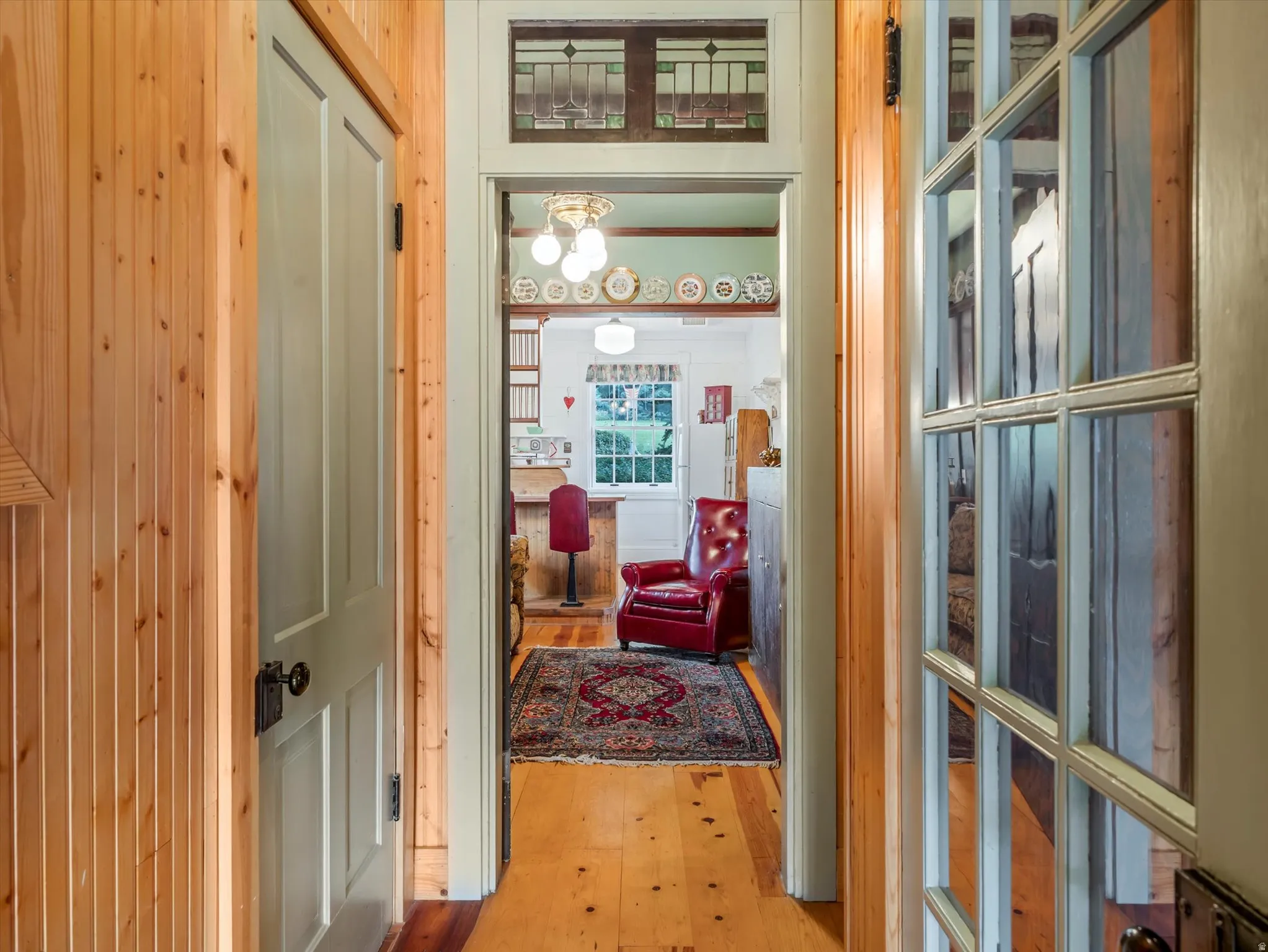Hallway featuring vertical wood paneling and light wood-finish flooring