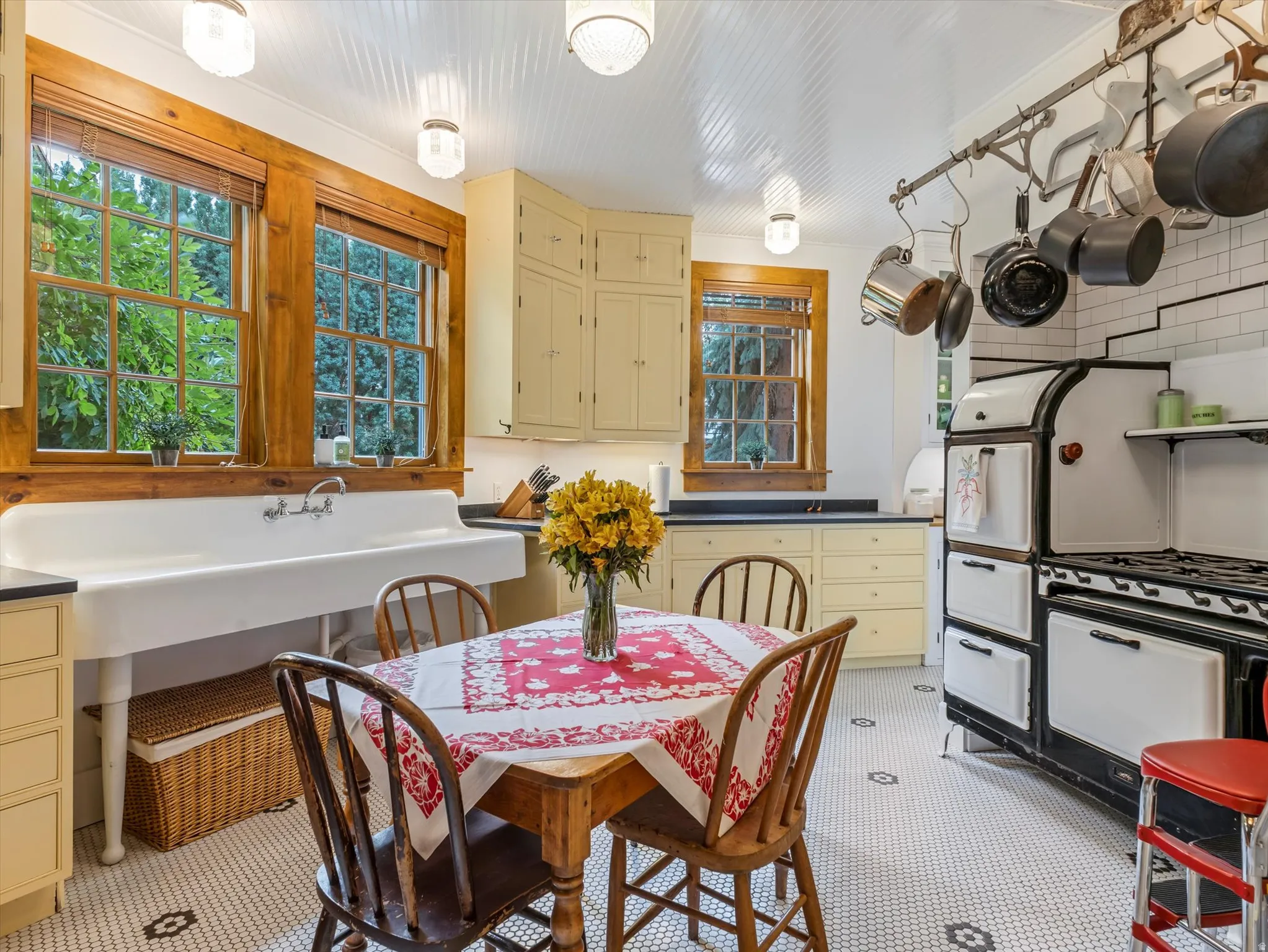 Kitchen featuring a classic white farmhouse sink, mosaic tile flooring, cream-painted cabinetry, a vintage-style range, and natural wood window trim