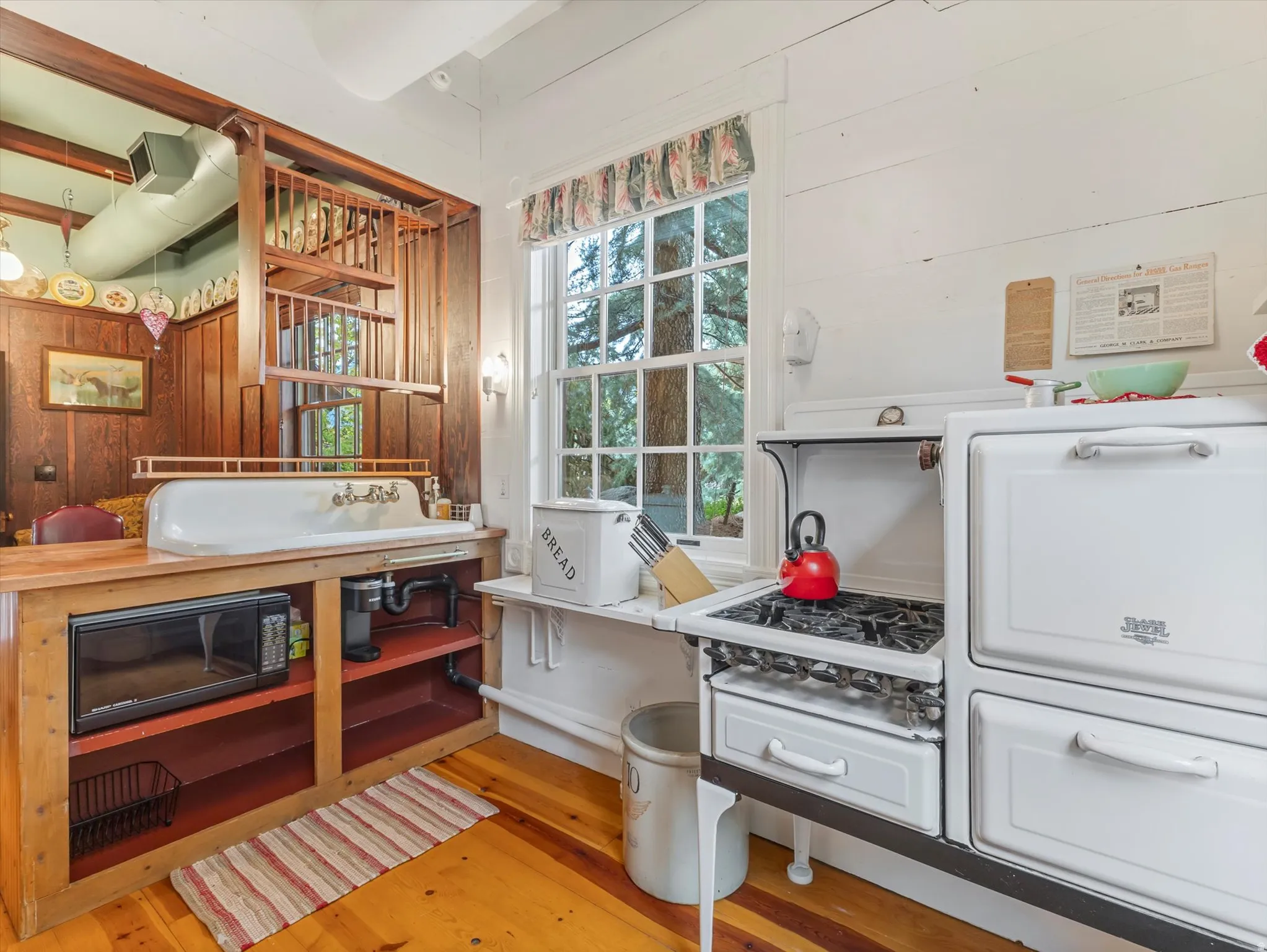 ADU Bright kitchen featuring a white enamel range, farmhouse sink, wood-finish flooring, white shiplap walls, and a multi-pane window