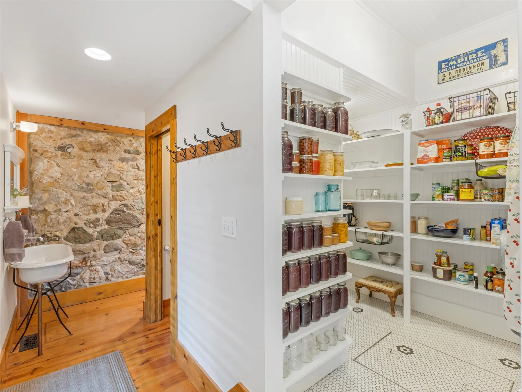Spacious pantry featuring extensive shelving, beadboard accents, and a hexagonal mosaic tile floor