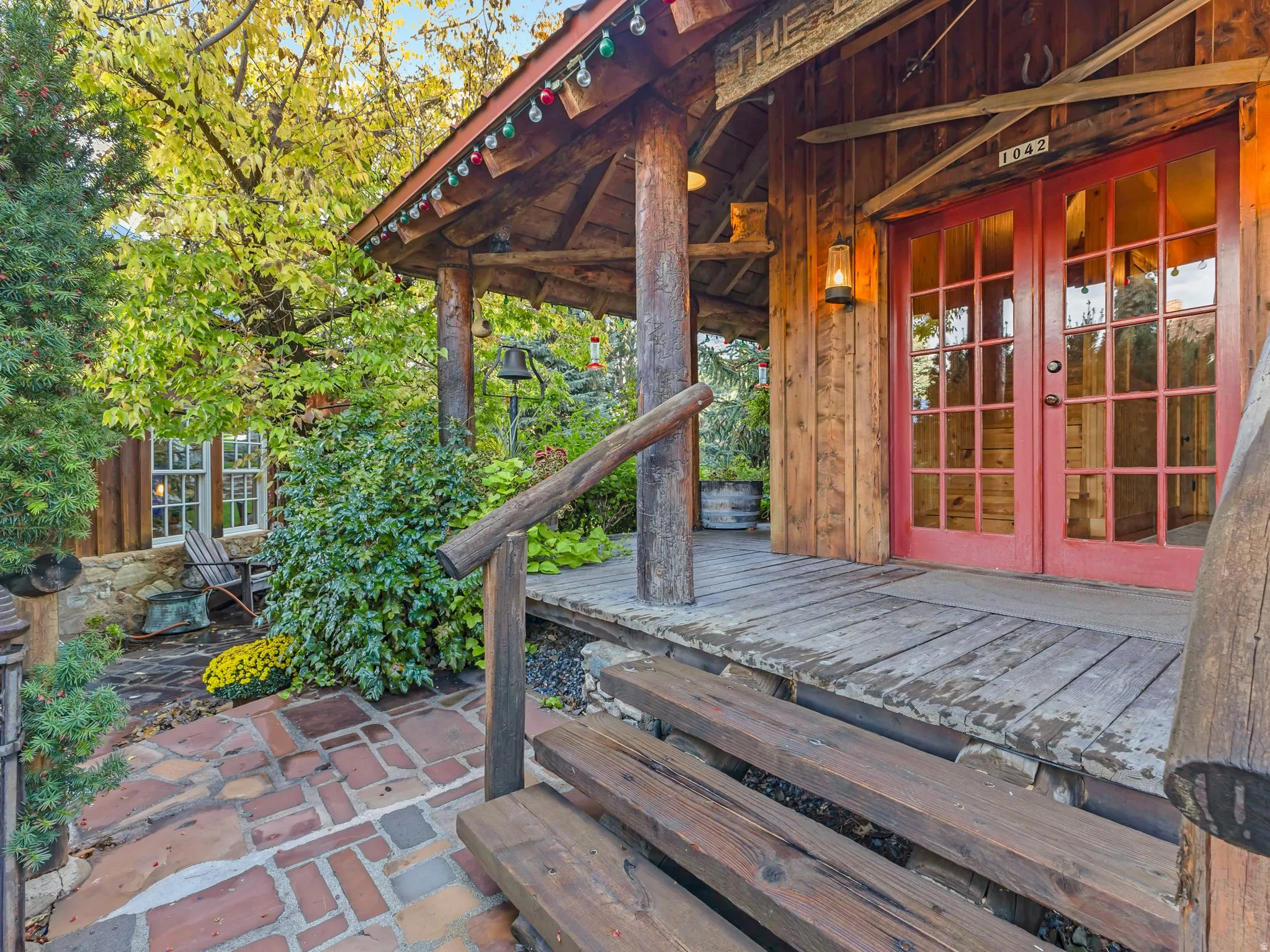 ADU entrance featuring a covered porch, wood-finish flooring, and red-paned double doors