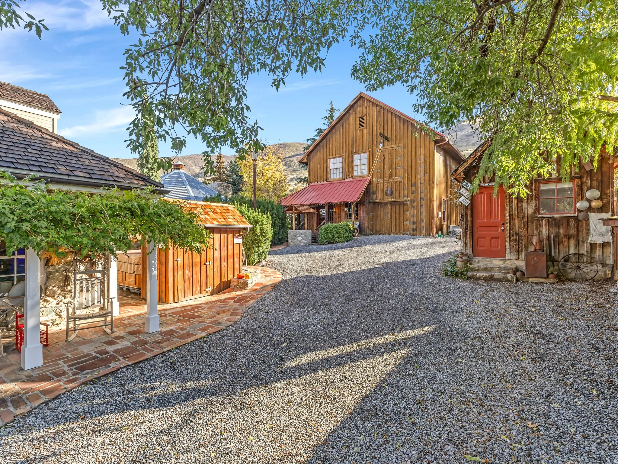 Gravel driveway leading to multiple wood-sided structures with various rooflines