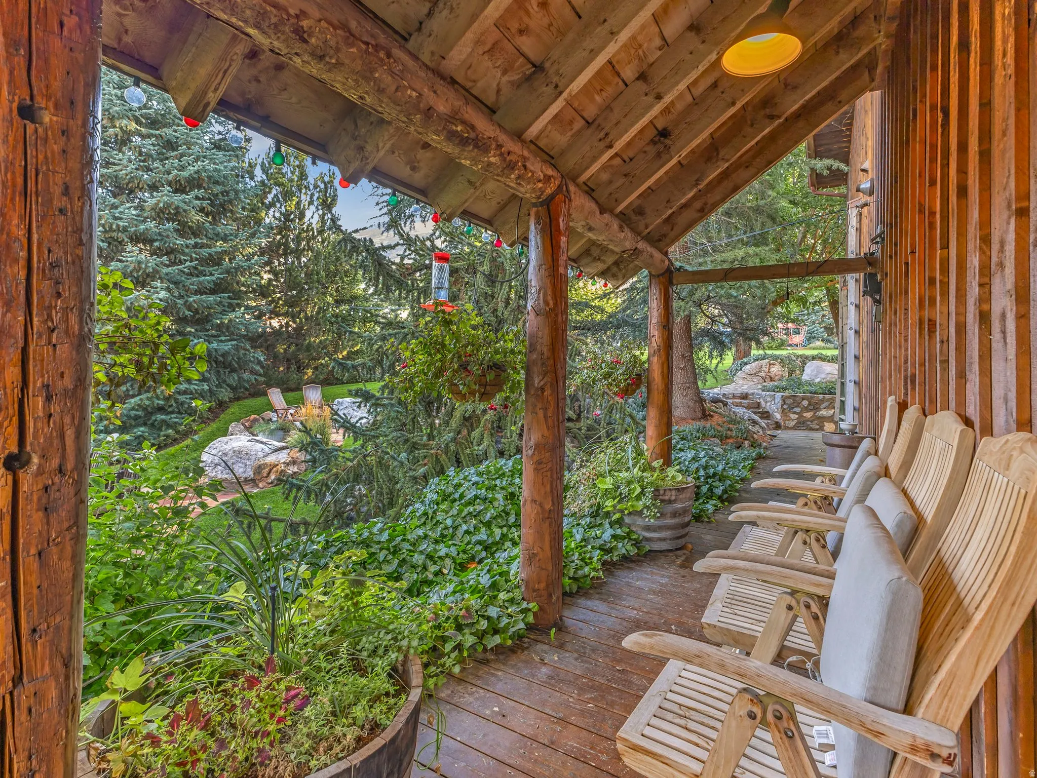 Expansive covered porch featuring a natural wood ceiling, log support beams, and wood-finish flooring