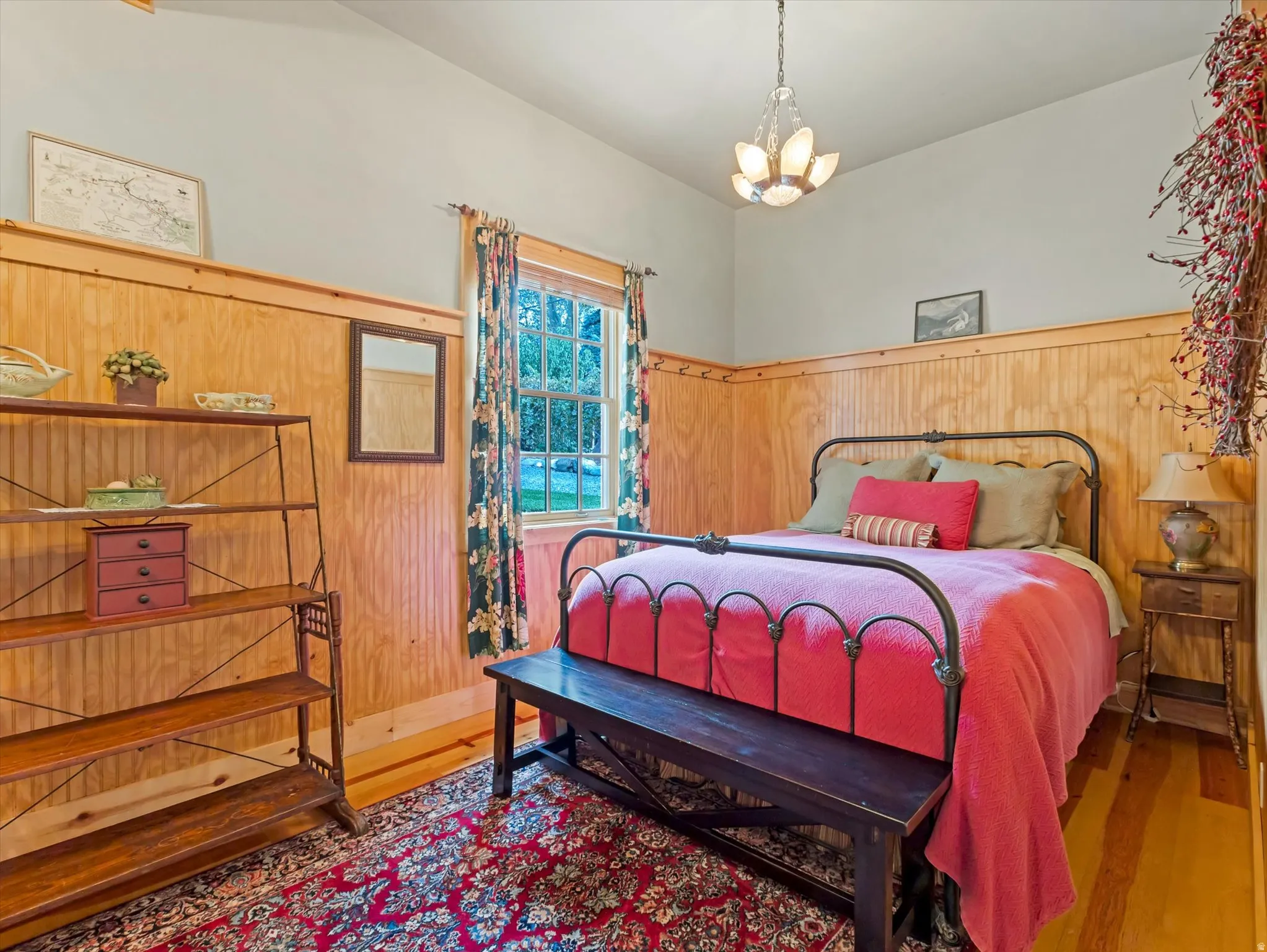 ADU Bedroom featuring light wood paneling, wood-finish flooring, a decorative chandelier, and a window with trim