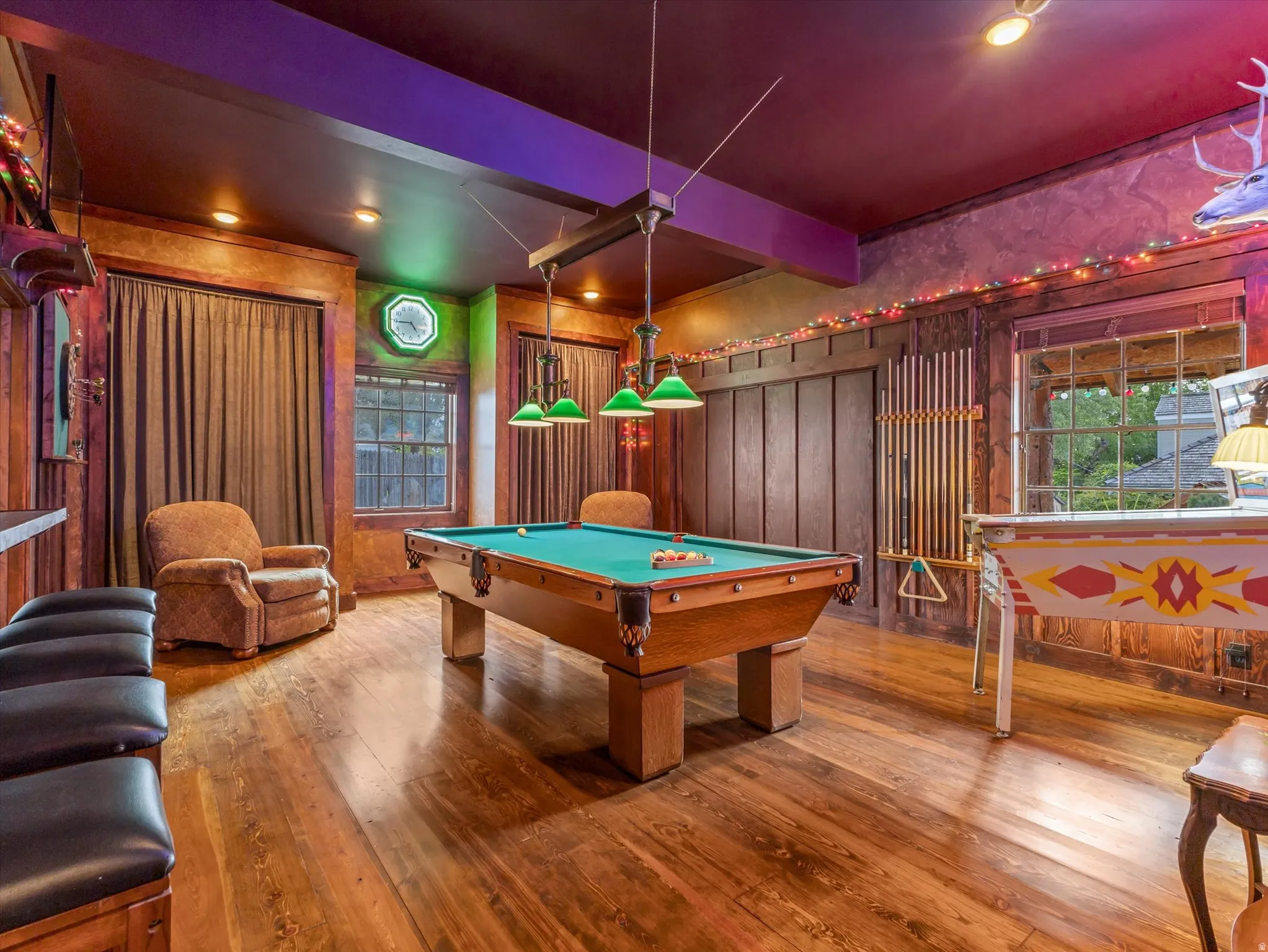 Garage/Recreation room featuring a pool table with overhead lighting, wood-finish flooring, wood paneling, and multiple windows