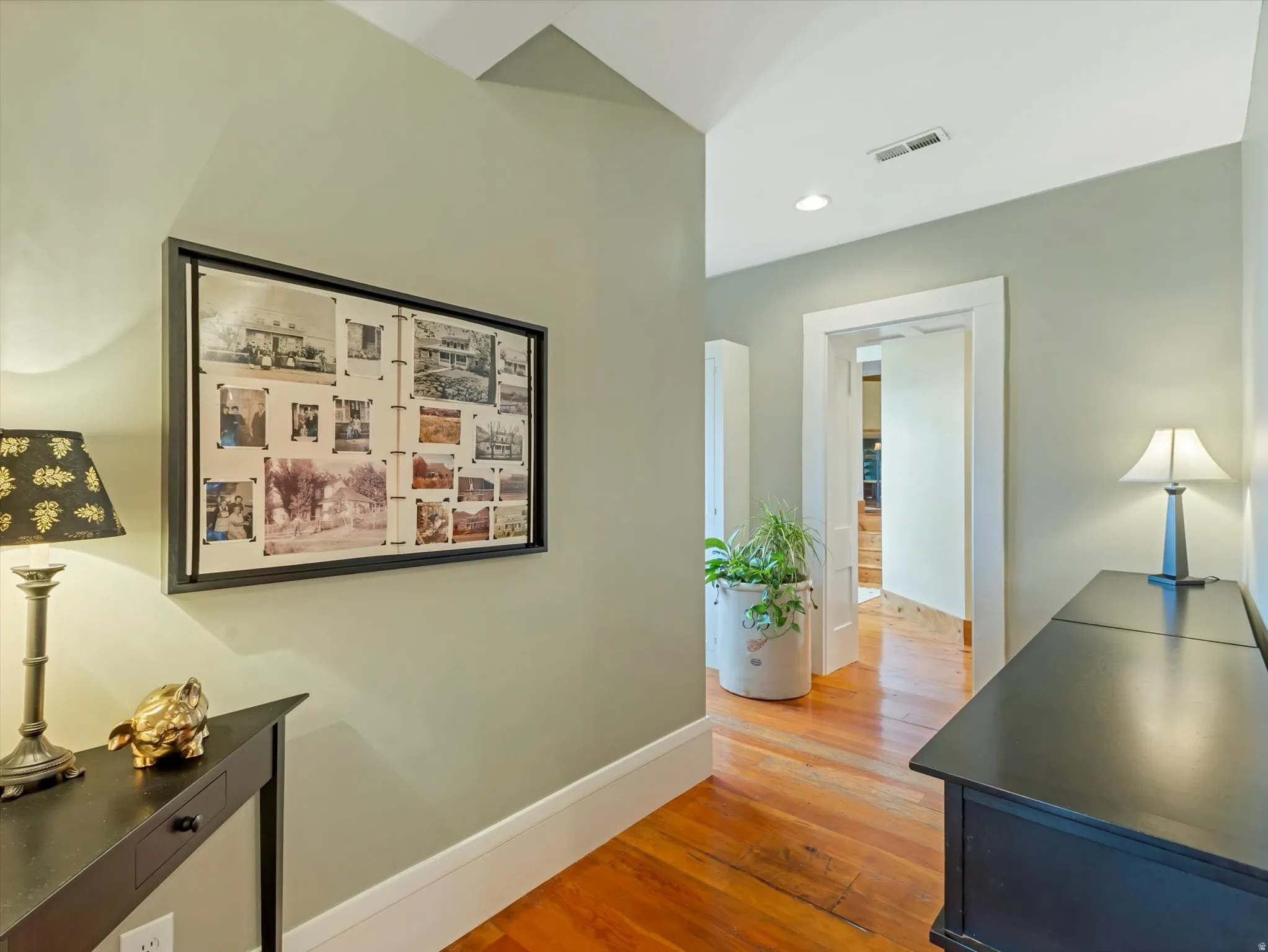 Hallway featuring wood-finish flooring, light green wall paint, white trim, recessed lighting, and a vaulted ceiling
